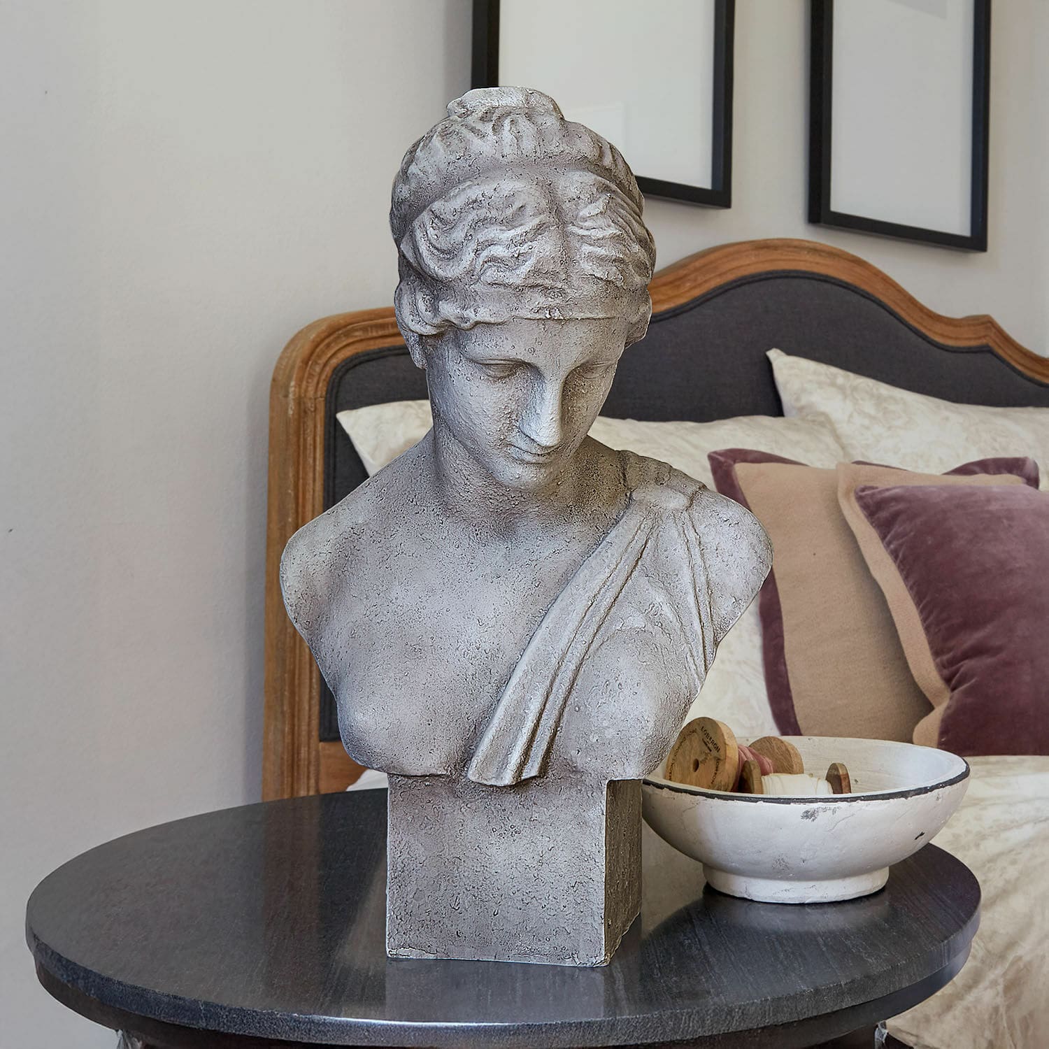 Busto Castolio Busto in pietra grigia su tavolo nero in interno elegante con cuscini decorativi