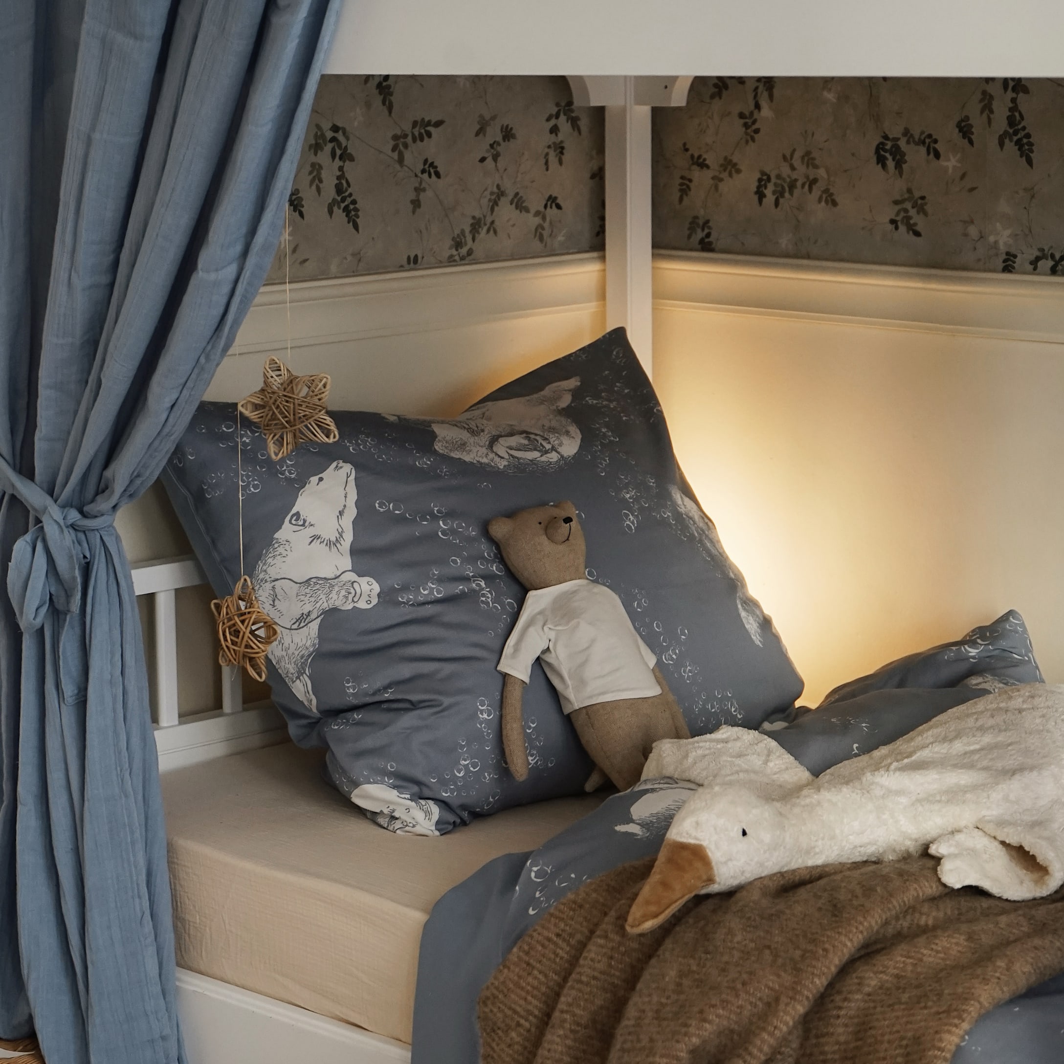 Biancheria da letto blu con motivo orso e peluche su letto per bambini in stanza accogliente