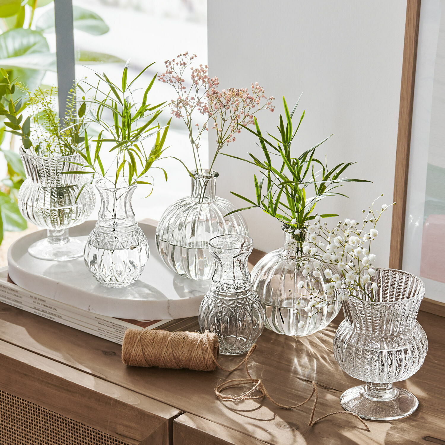 Set di sei vasetti Amber Set di vasi in vetro trasparente con fiori verdi e bianchi su mobile in legno