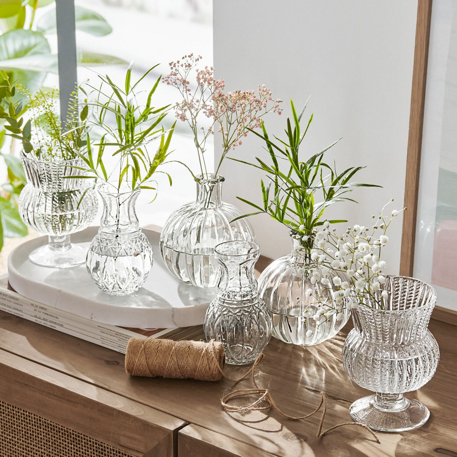 Set di sei vasetti Amber Set di vasi in vetro trasparente con fiori verdi e bianchi su mobile in legno