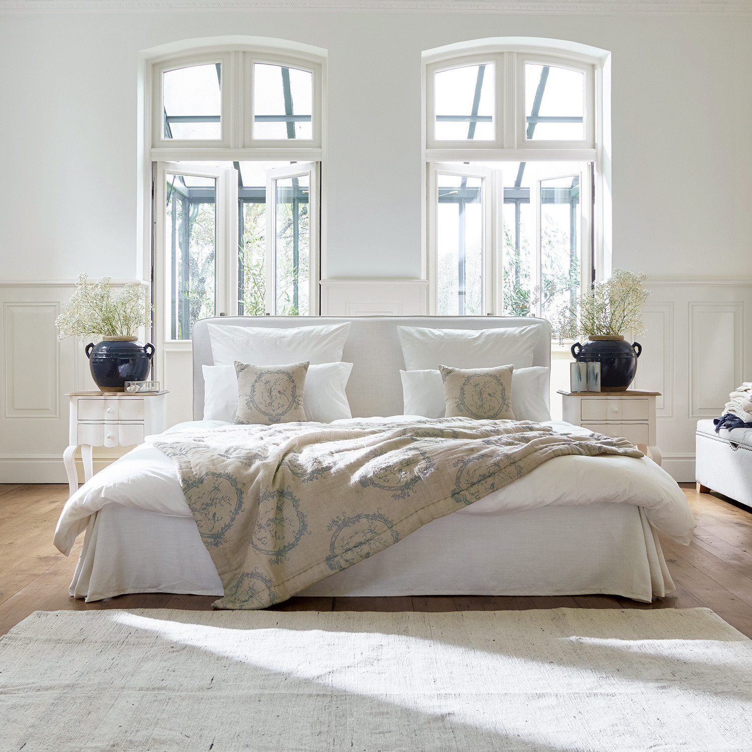 Letto Aubrianne Letto accogliente con rivestimento chiaro e coperta beige decorata in camera luminosa con grandi finestre