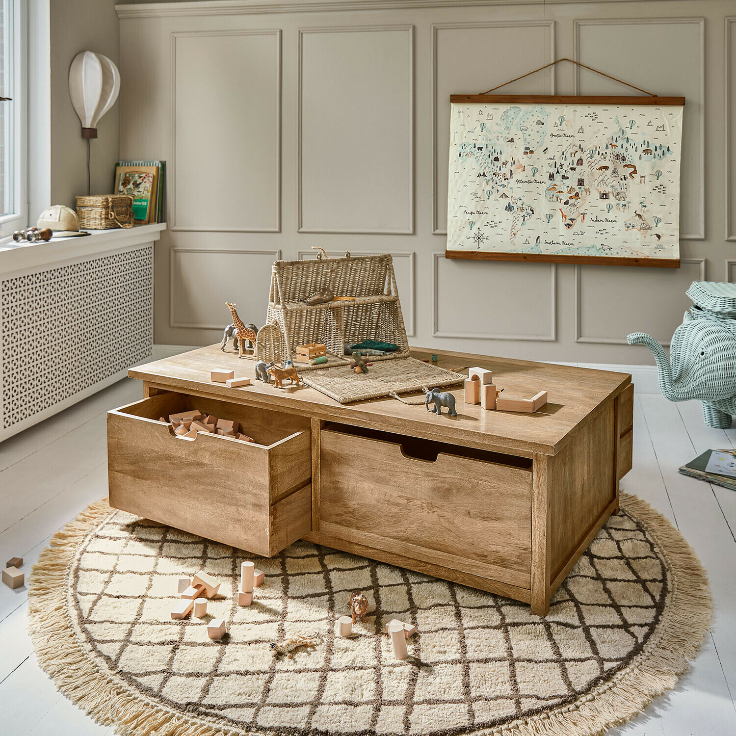 Tavolino da gioco in legno con cassetti e blocchi di legno su tappeto rotondo in camera dei bambini