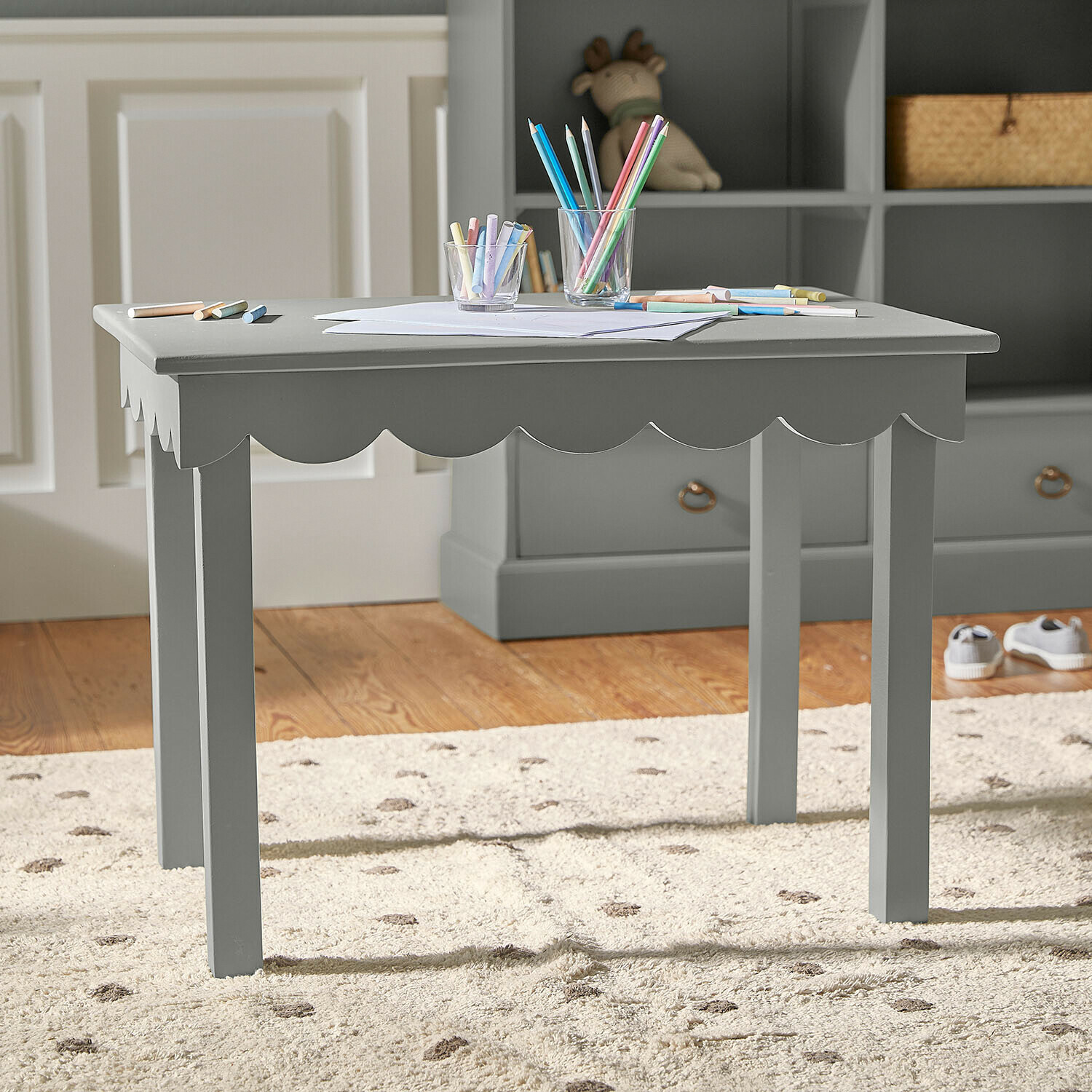 Tavolo in legno verde per bambini con bordo ondulato e matite colorate sul piano per disegnare