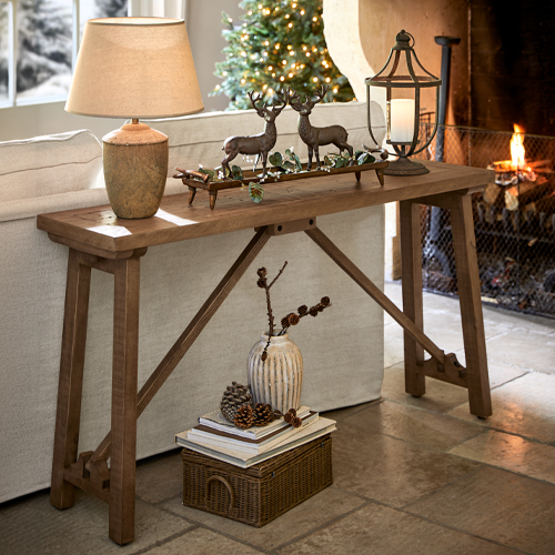 Tavolo consolle in legno colore naturale con lampada e decorazioni di renne in soggiorno accogliente con camino