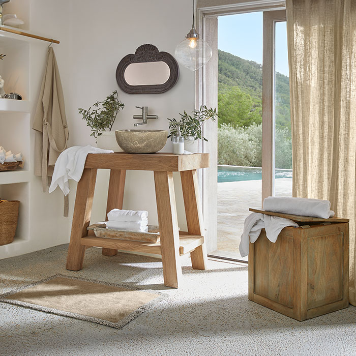 Bagno con mobile in legno e lavabo in pietra, colori naturali e piante decorative