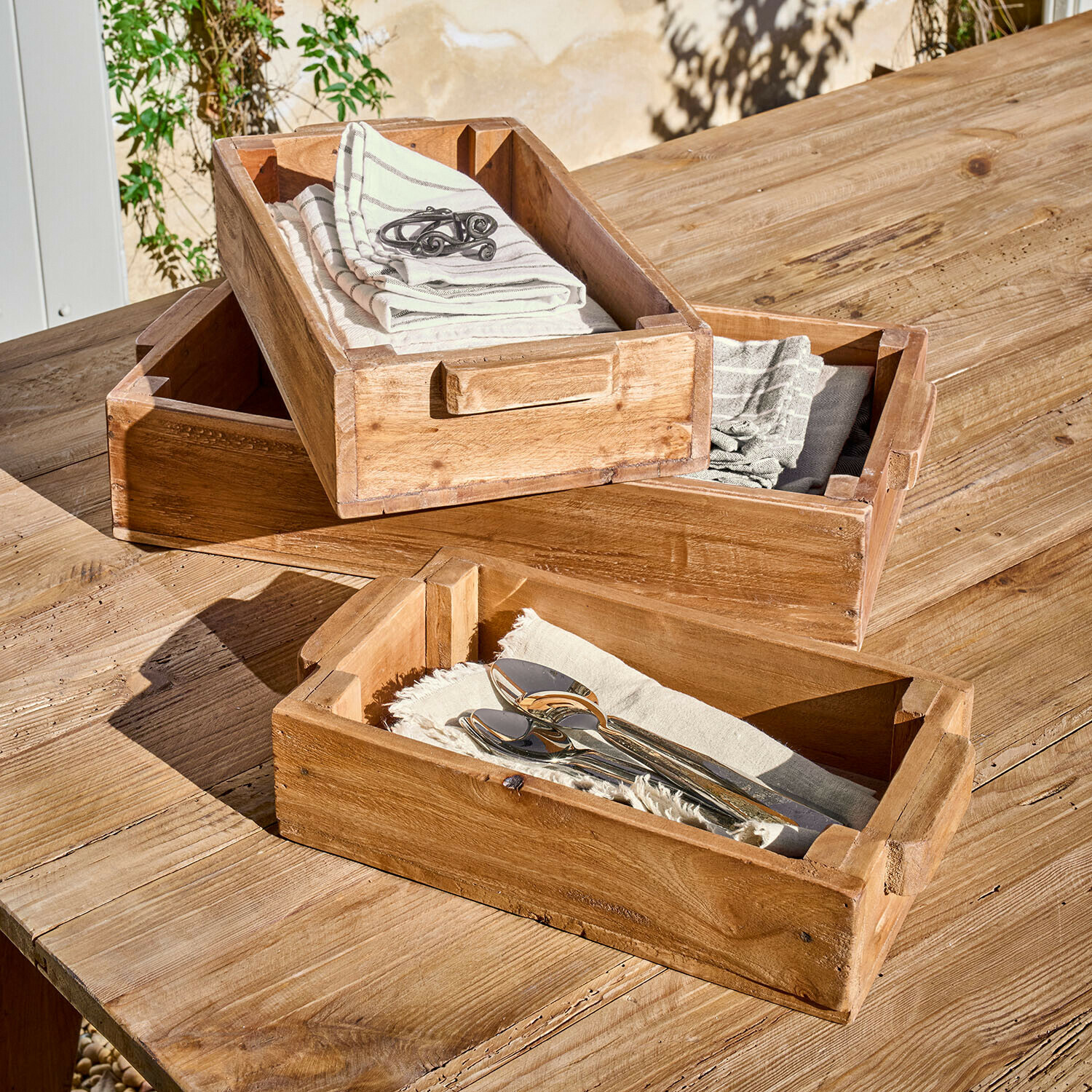 Set di 3 scatole Tarevo Set di tre vassoi in legno naturale con manici su tavolo in legno, con tovaglioli e posate