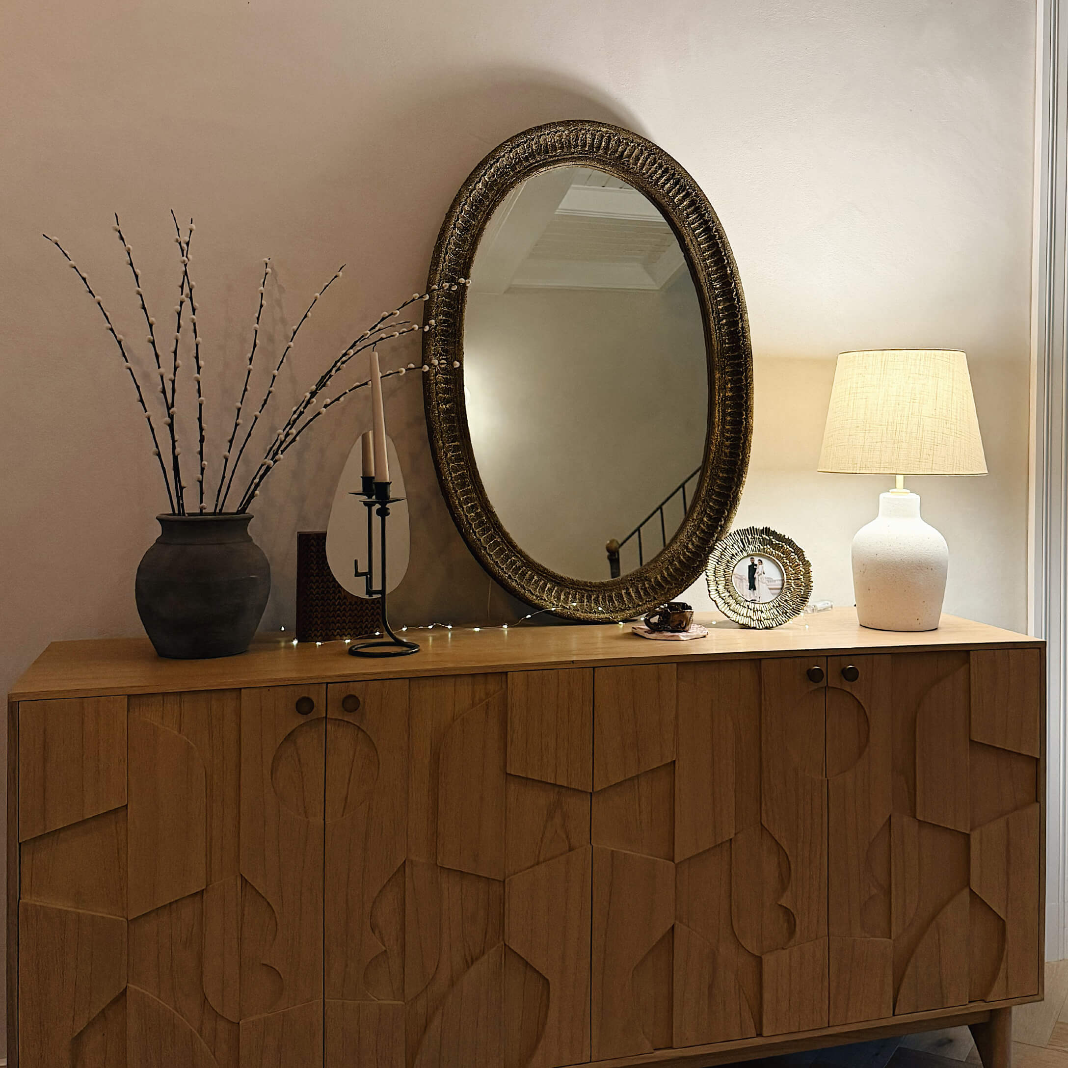 Credenza in legno con motivo geometrico, specchio decorativo e lampada sul tavolo nel soggiorno