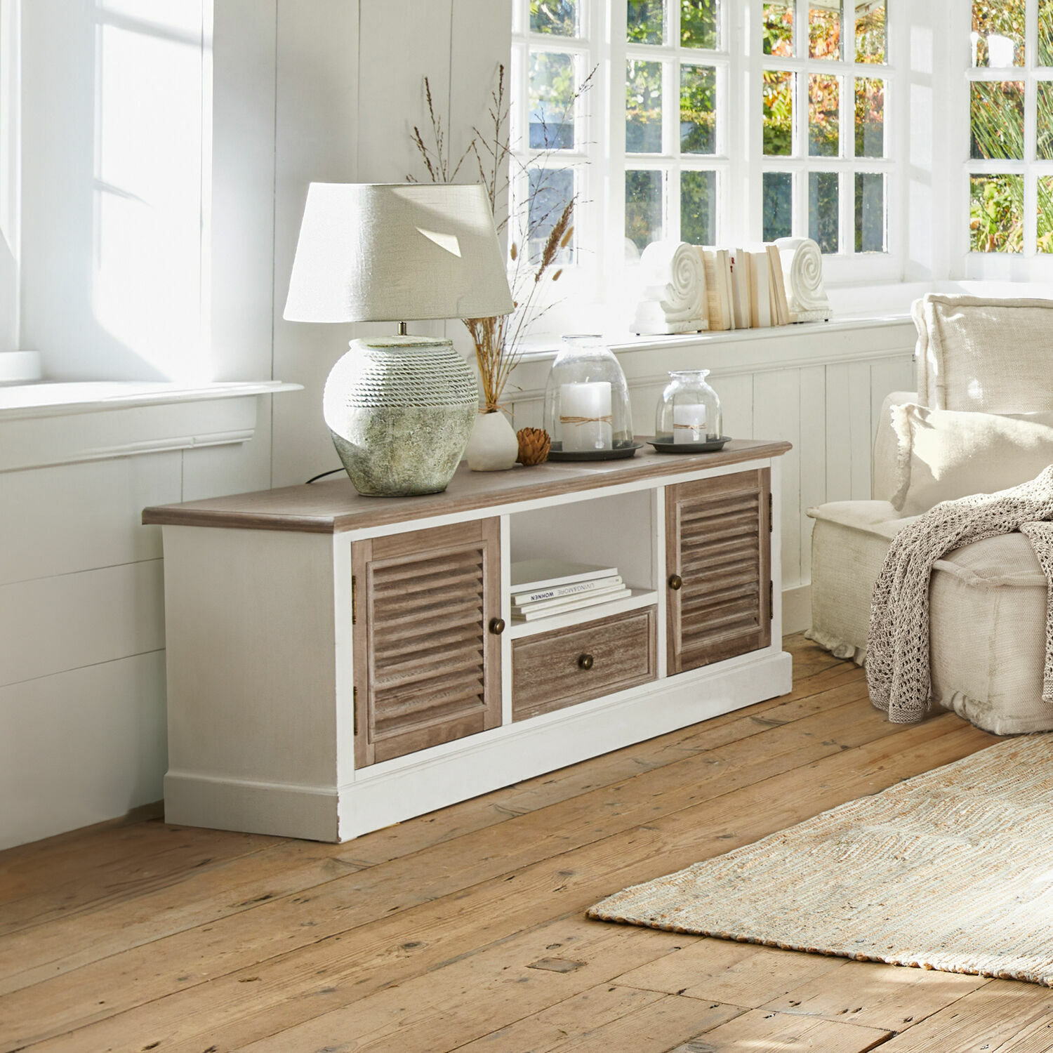 Credenza Glencoe Mobile rustico in legno bianco con ante marroni, lampada e decorazioni sul piano in soggiorno luminoso