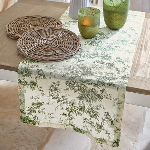 Runner da tavola crema con motivo vegetale verde, decorazione con sottobicchieri in rattan e bicchieri verdi