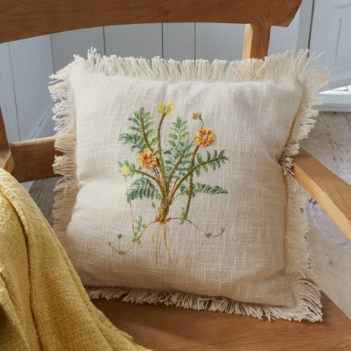 Cuscino in lino beige con frange e ricamo floreale su sedia in legno chiaro