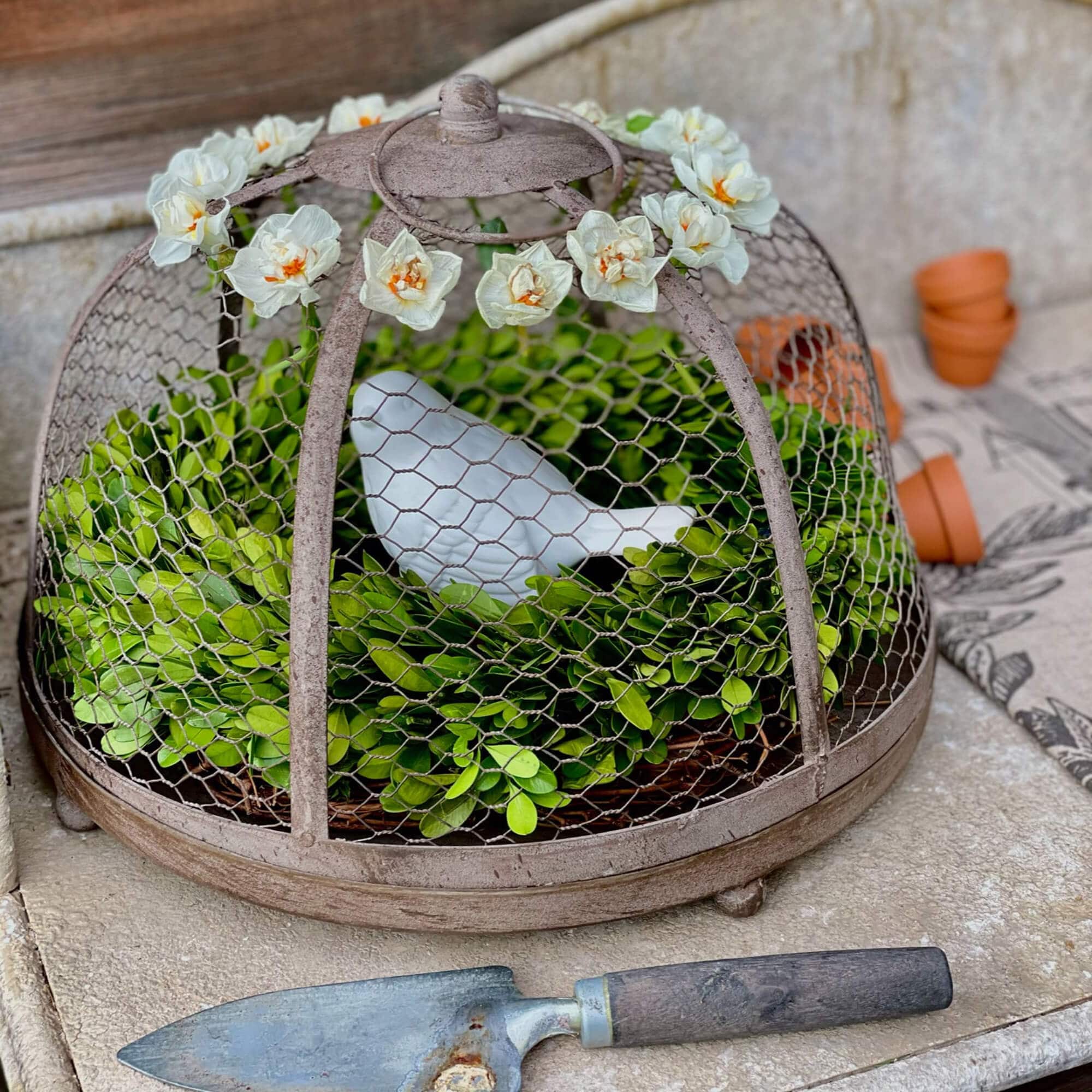 Decorazione da giardino in metallo con foglie verdi e uccello bianco in ceramica sotto campana fiorita