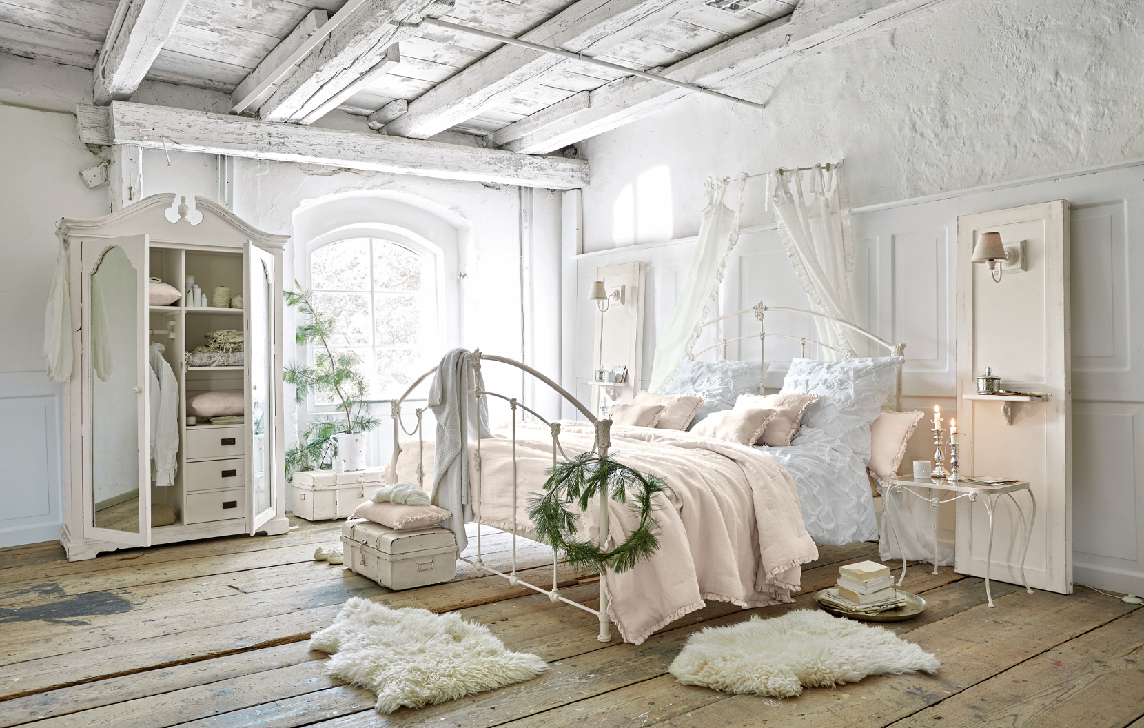 Camera shabby chic con letto in metallo bianco e biancheria da letto pastello su pavimento in legno