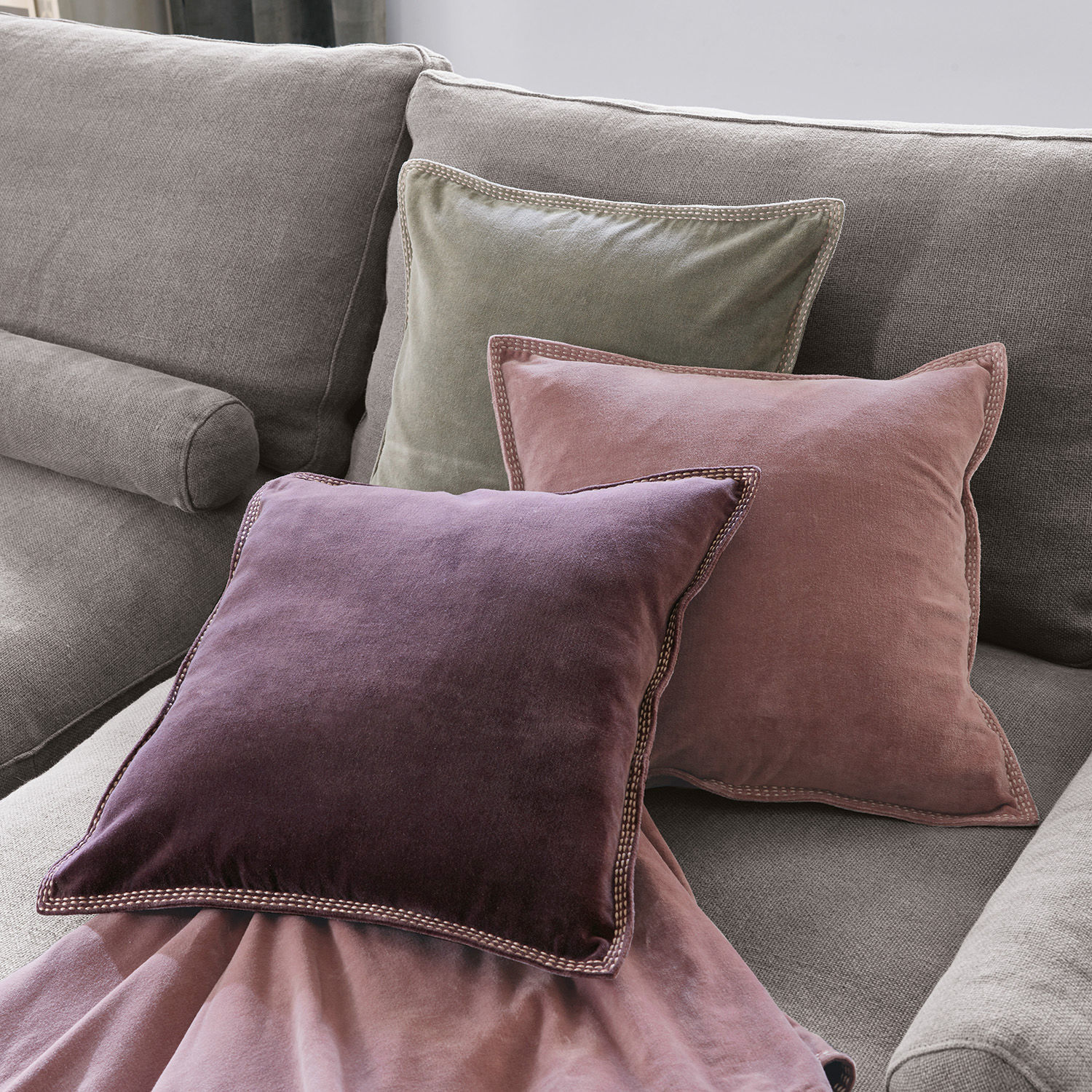 Set di 3 cuscini Allonnes Set di tre cuscini in velluto viola, rosa e verde su divano grigio