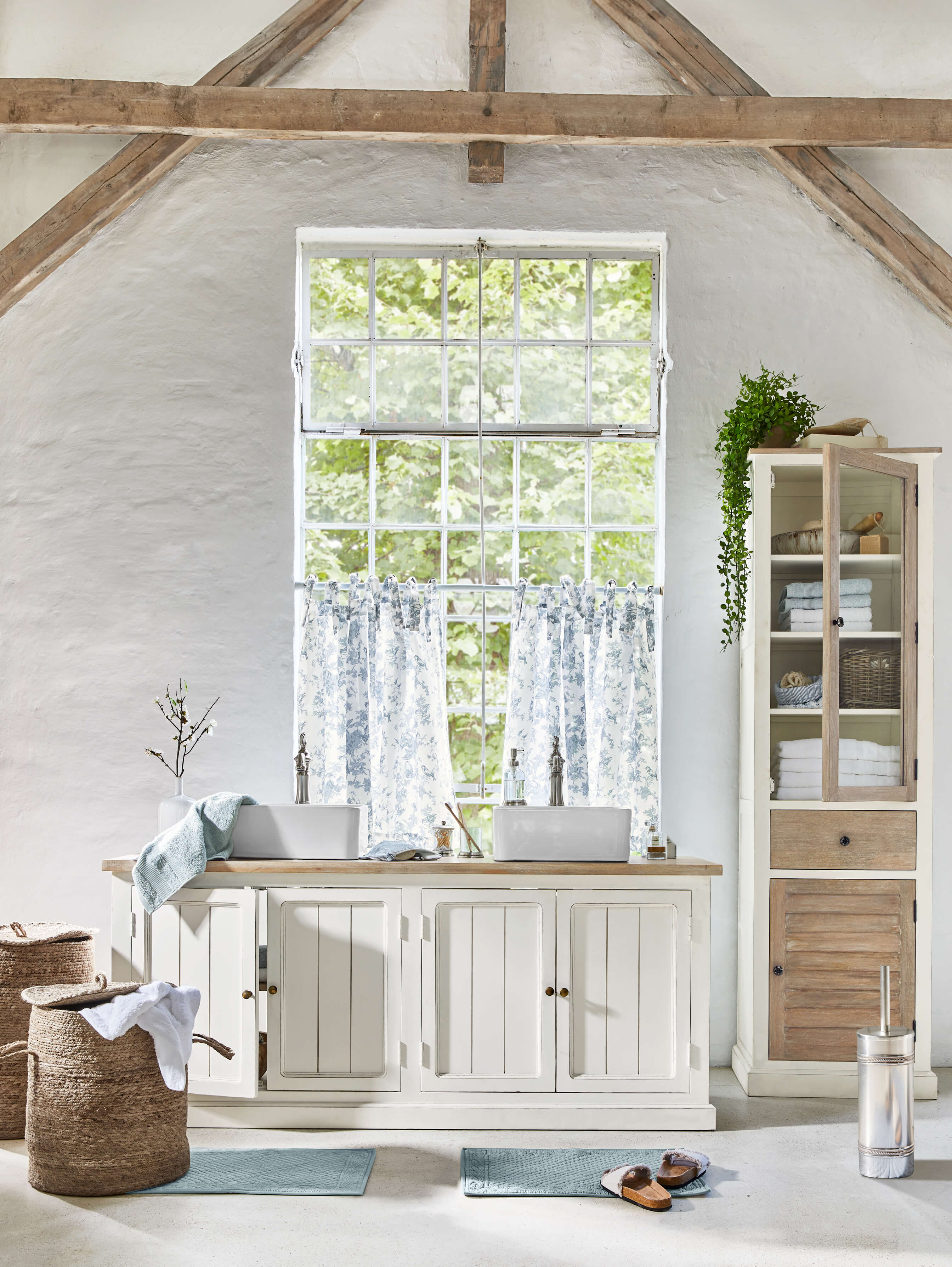 Mobile bagno bianco in legno con due lavandini e tende blu in interno rustico