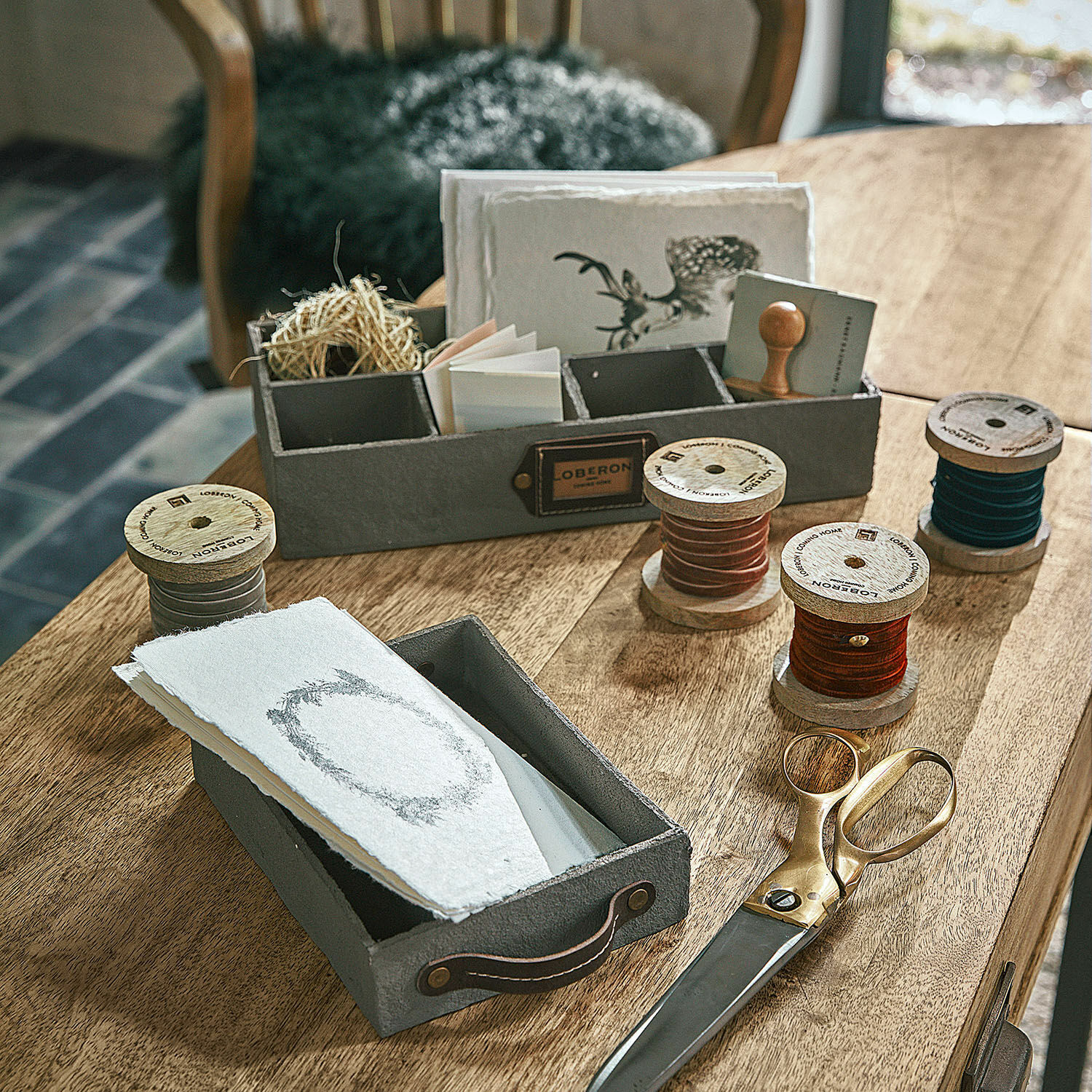 Set di 4 nastri di velluto Hilary Scatole in feltro grigio con manici e bobine di legno con cordoncini colorati su tavolo in legno