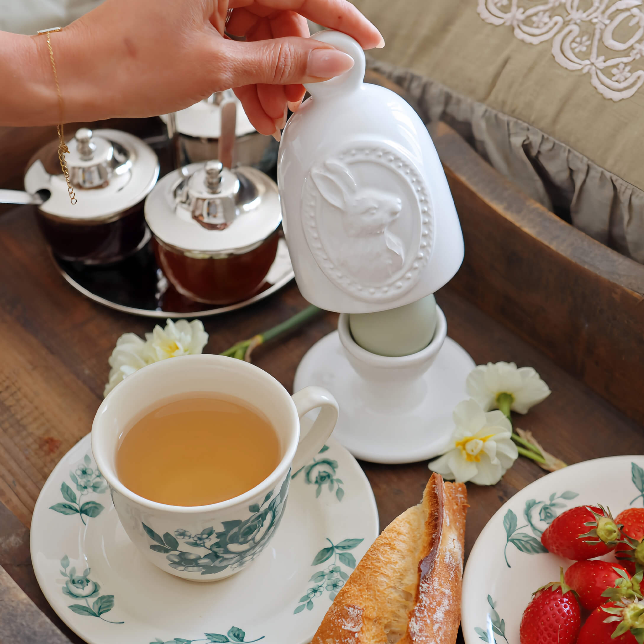 Contenitore in ceramica bianca con motivo coniglio su tavola da colazione con tè e fragole