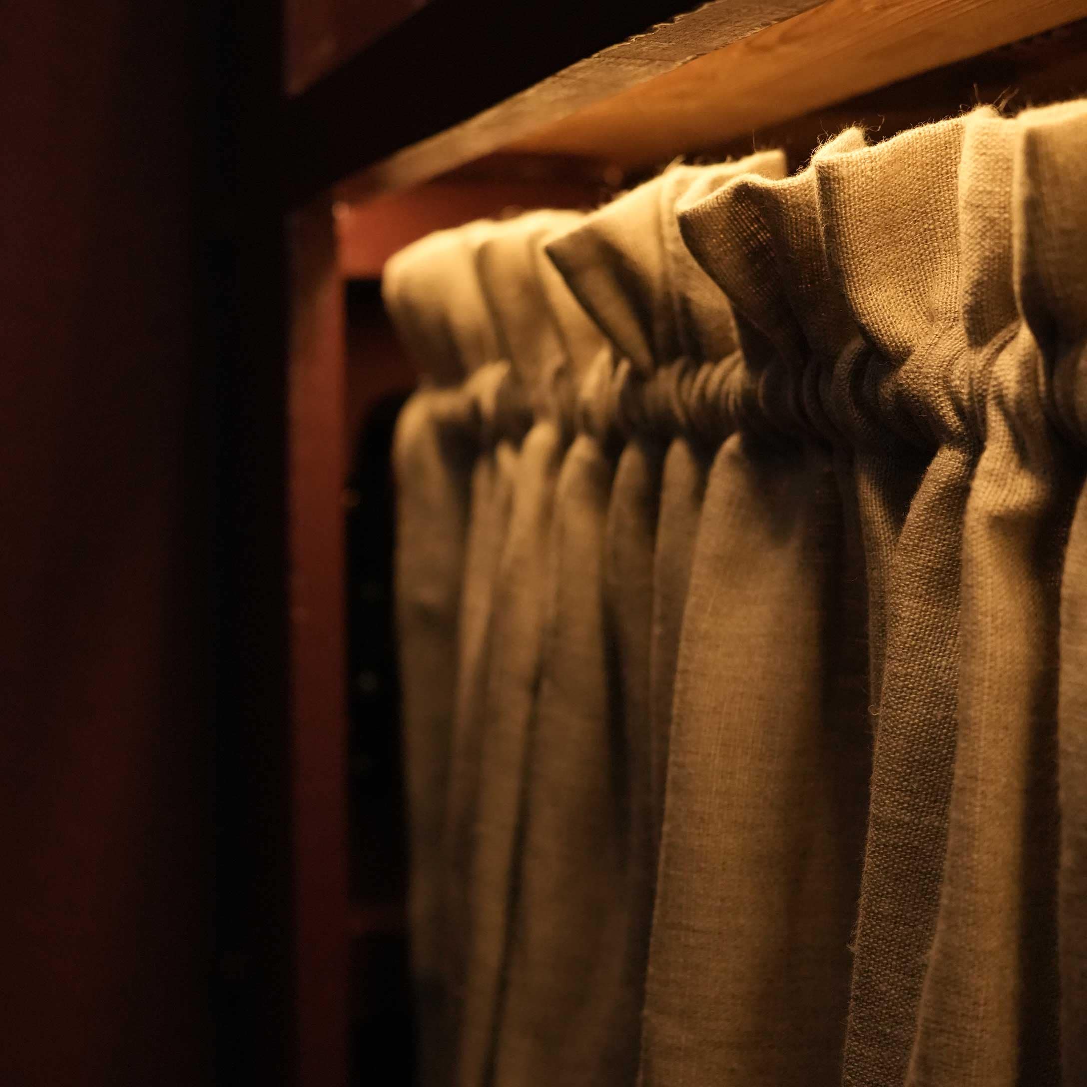 Tenda in lino beige plissettata su bastone di legno con luce calda