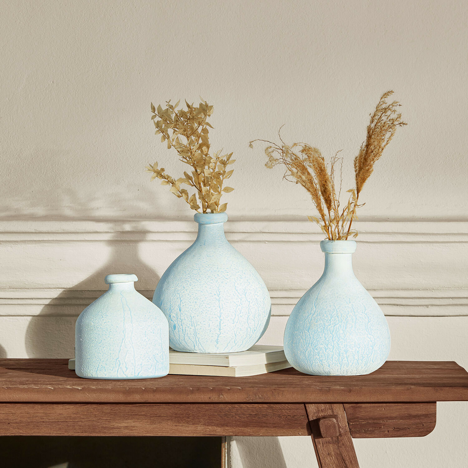 Set di 3 vasi Donara Set di tre vasi in ceramica azzurra con piante essiccate su tavolo in legno per decorazione d'interni