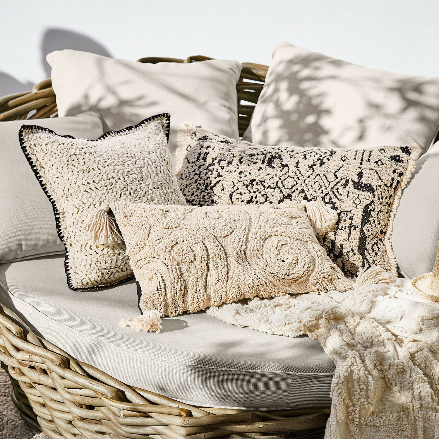 Set di 3 copricuscini Norlinn Set di cuscini decorativi crema in materiale morbido su divano in vimini, stile boho