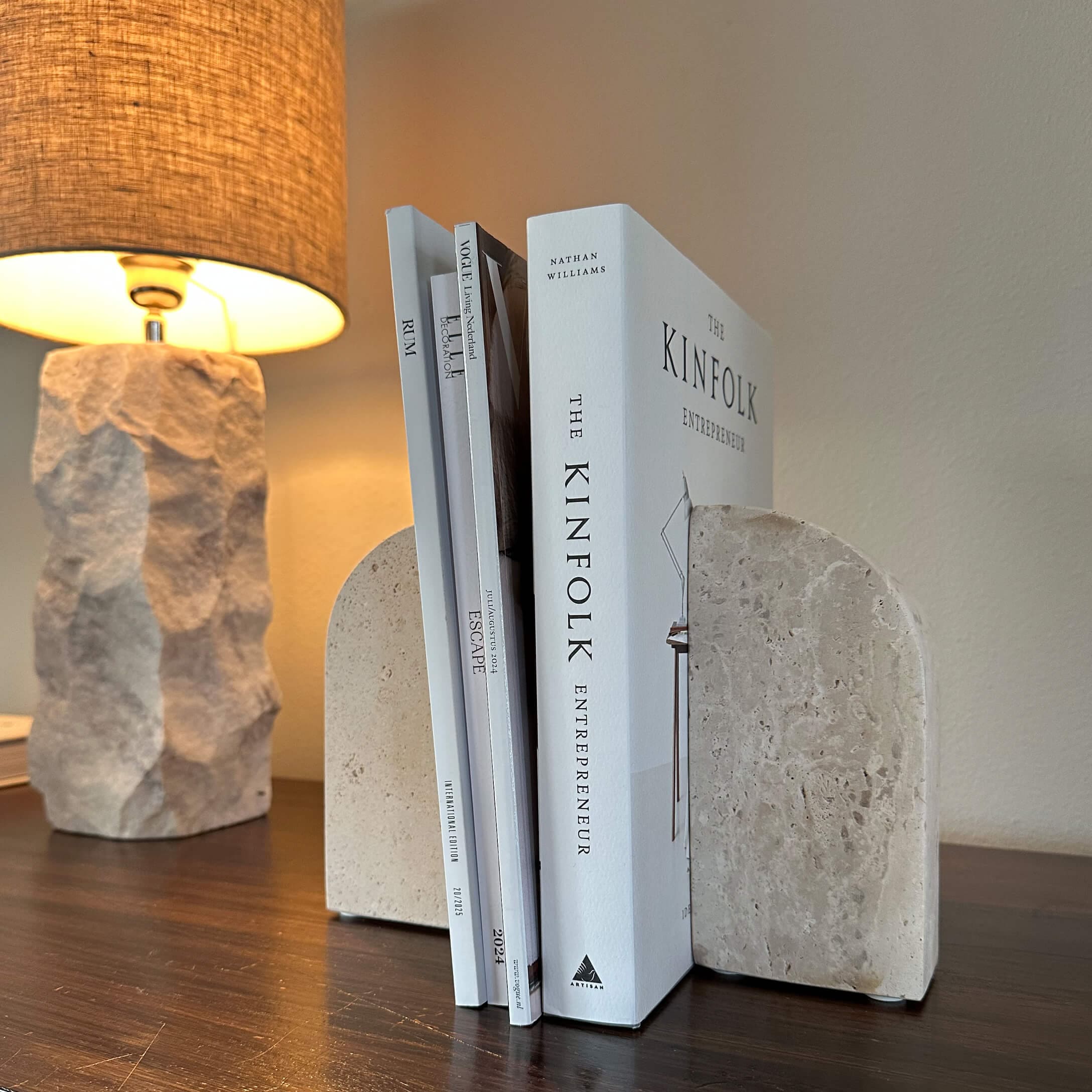Fermalibri in pietra beige su tavolo in legno con lampada accesa sullo sfondo