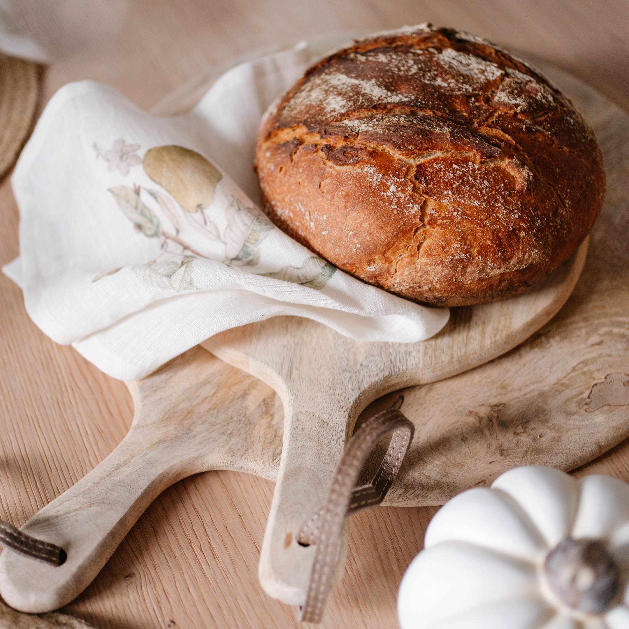 Pane su tagliere in legno con canovaccio di lino e zucca bianca decorativa su tavolo