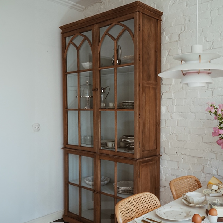Vetrina in legno con ante in vetro stile vintage in sala da pranzo con muro in mattoni bianchi