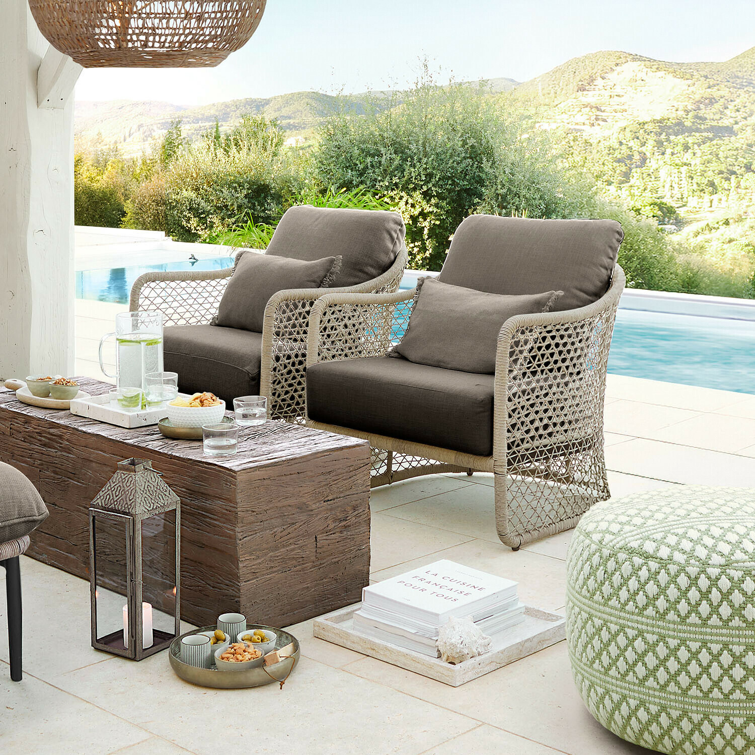 Set di mobili da esterno in rattan beige con cuscini grigi vicino alla piscina, salotto moderno e confortevole