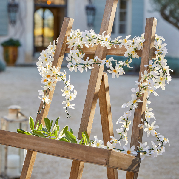 Cavalletto in legno con decorazione di fiori bianchi e foglie verdi all'aperto, decorazione da giardino