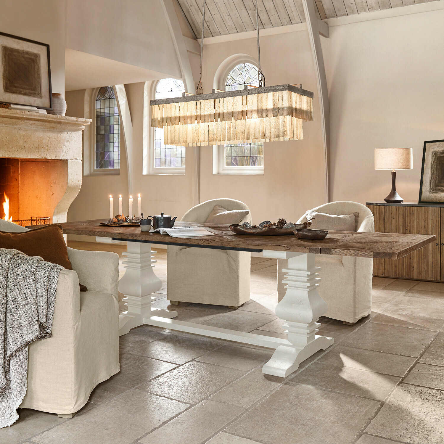 Tavolo Quillancourt Grande tavolo in legno con base bianca in soggiorno luminoso con camino e poltrone beige