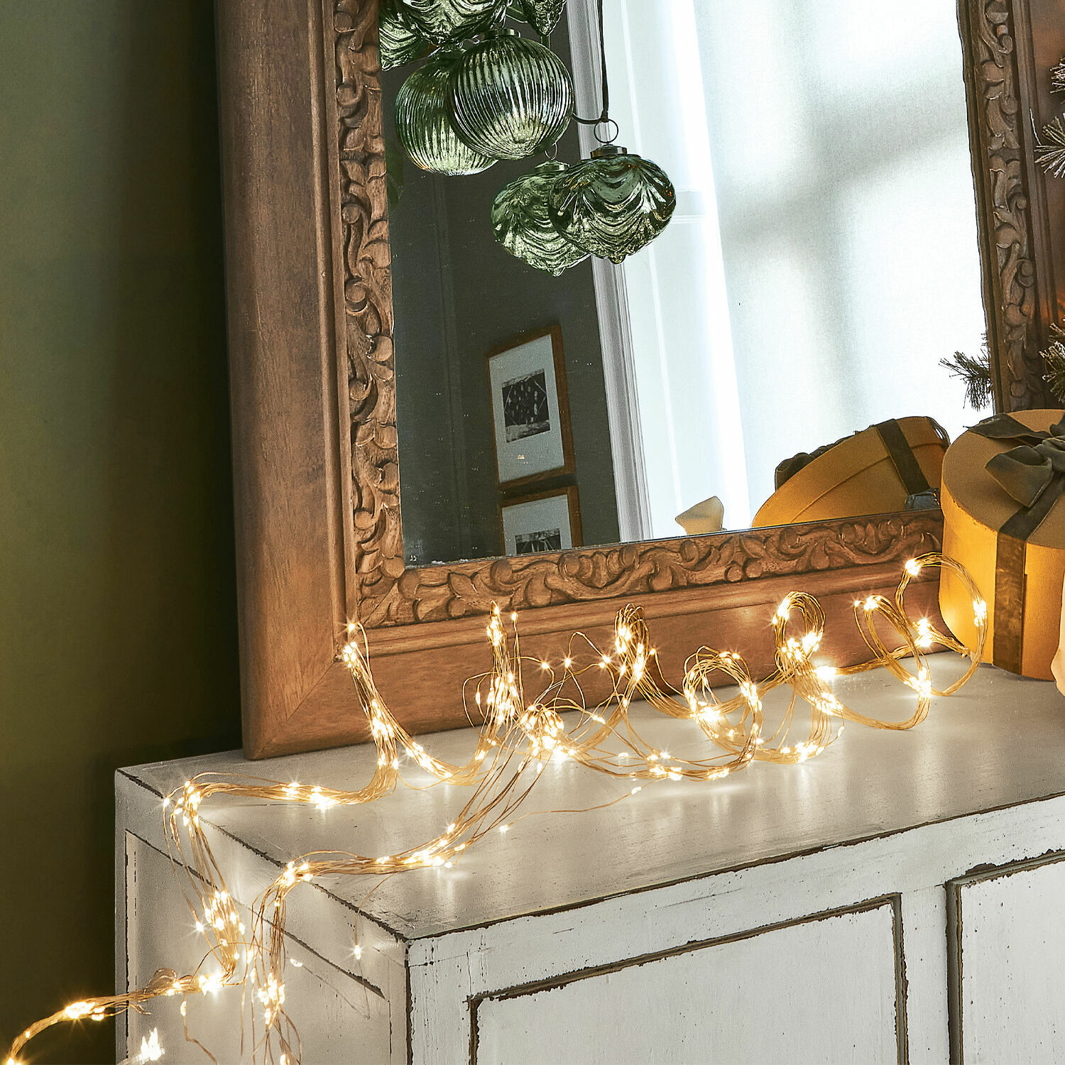 Catena luminosa Voltage Sottile catena luminosa LED su comò bianco con specchio in legno intagliato e decorazioni