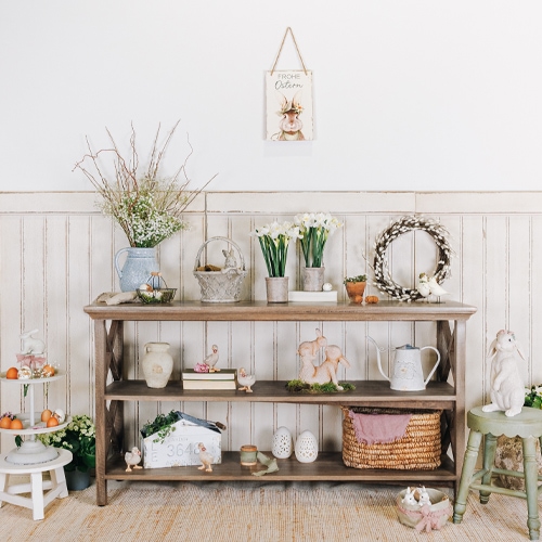Scaffale in legno con decorazioni pasquali, fiori e cesto di vimini in interno luminoso