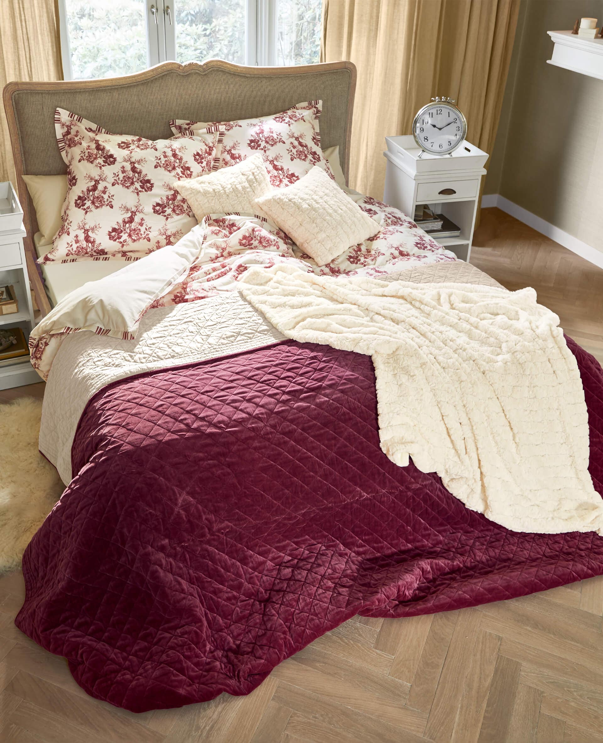 Biancheria da letto con motivo floreale rosso e coperta trapuntata bordeaux in camera accogliente