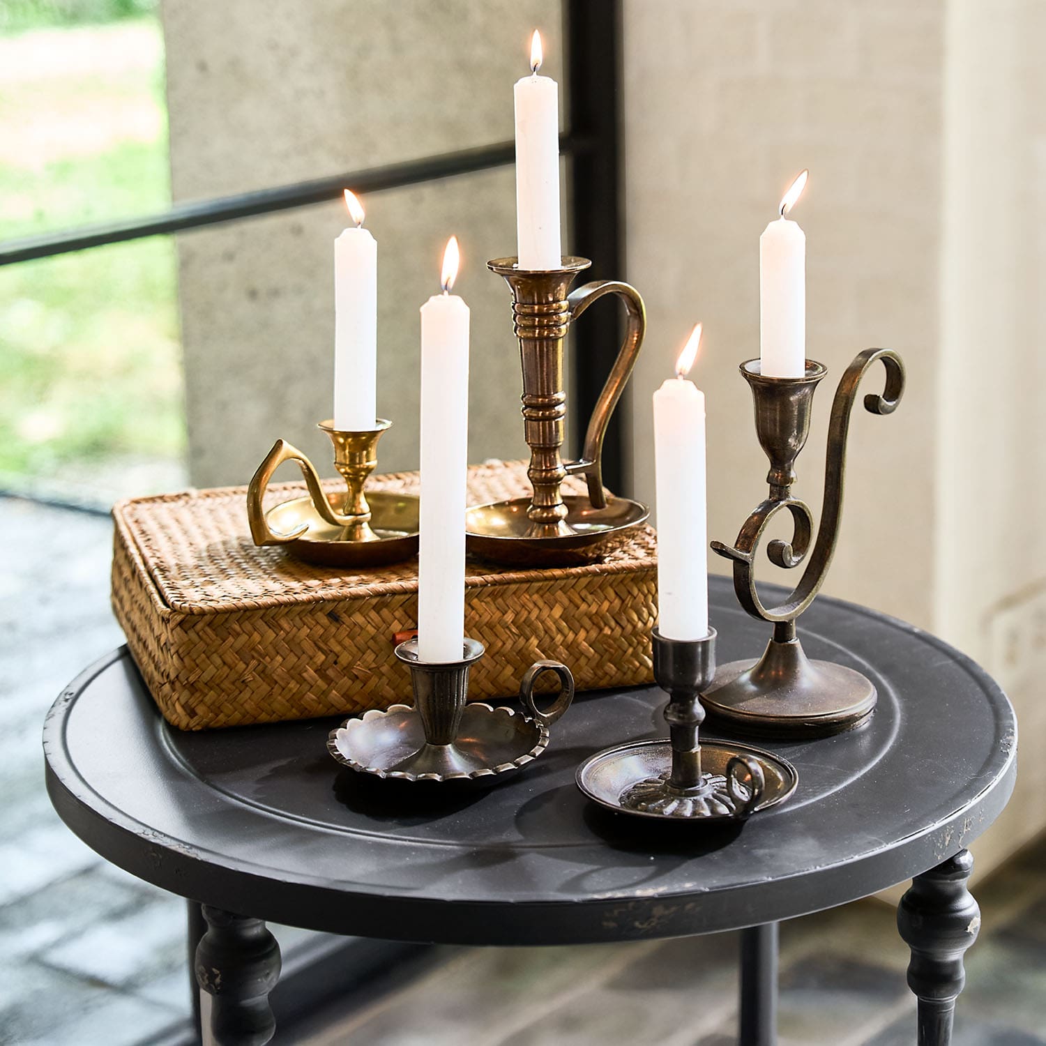 Set di candelabri in metallo con candele bianche su tavolo rotondo nero per decorazione d'interni
