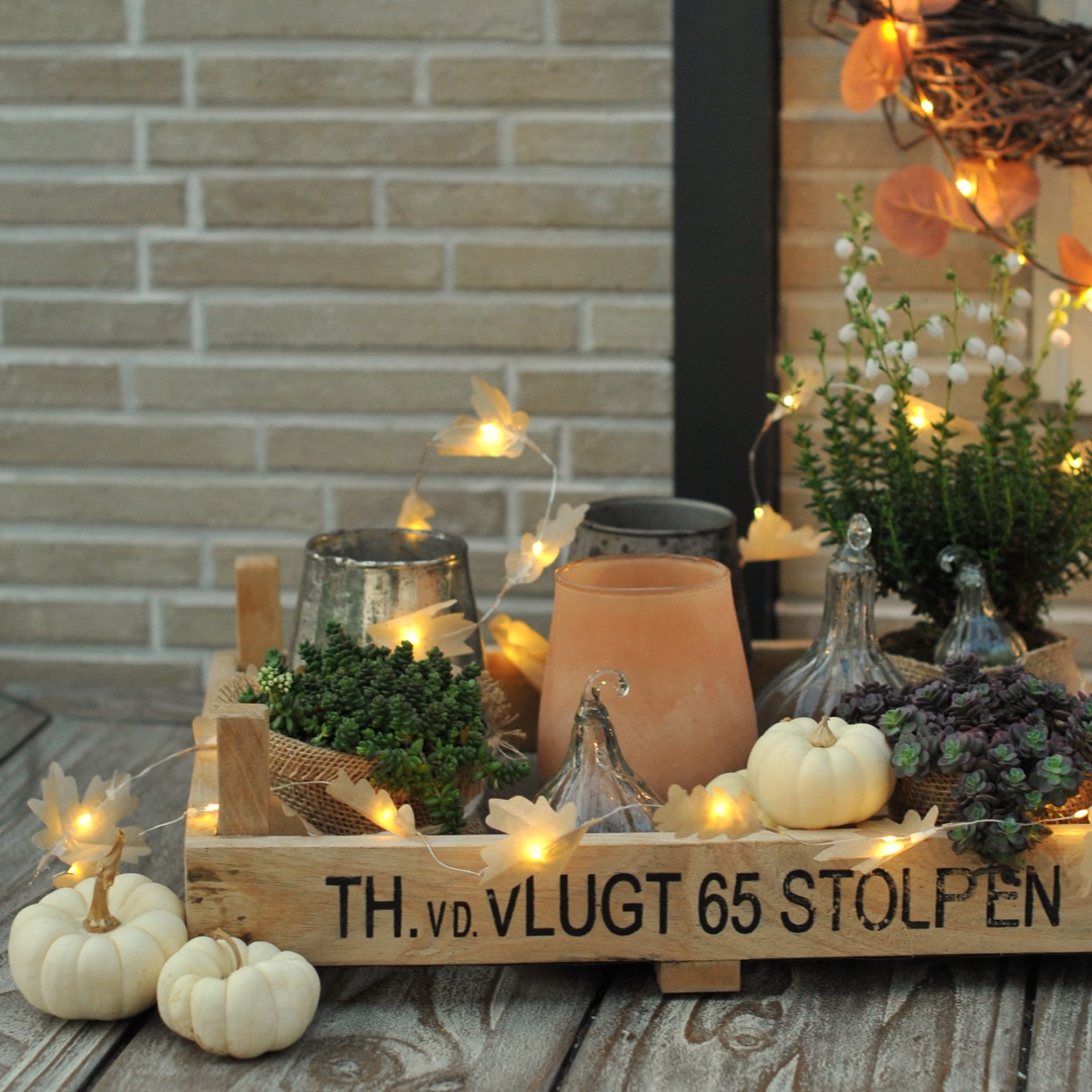 Cassetta di legno con decorazioni autunnali, zucche bianche, piante e luci LED su tavolo in legno