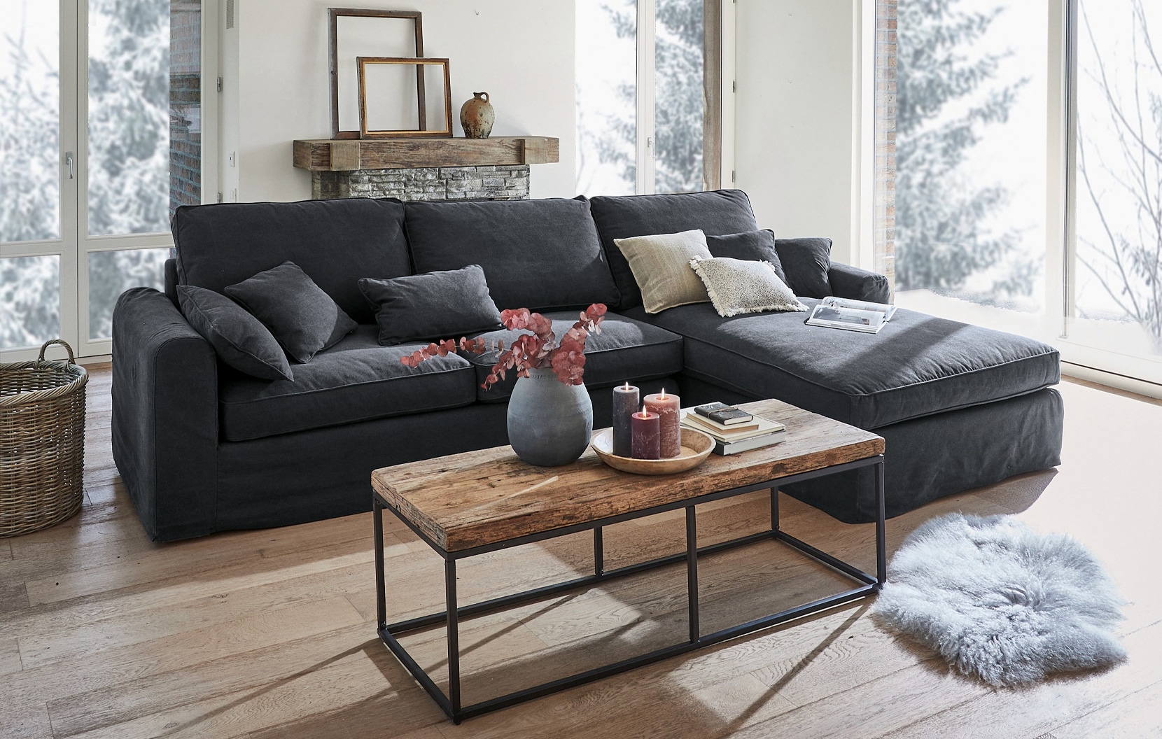 Divano angolare grigio in tessuto stile industriale con tavolino in legno e decorazioni in soggiorno luminoso