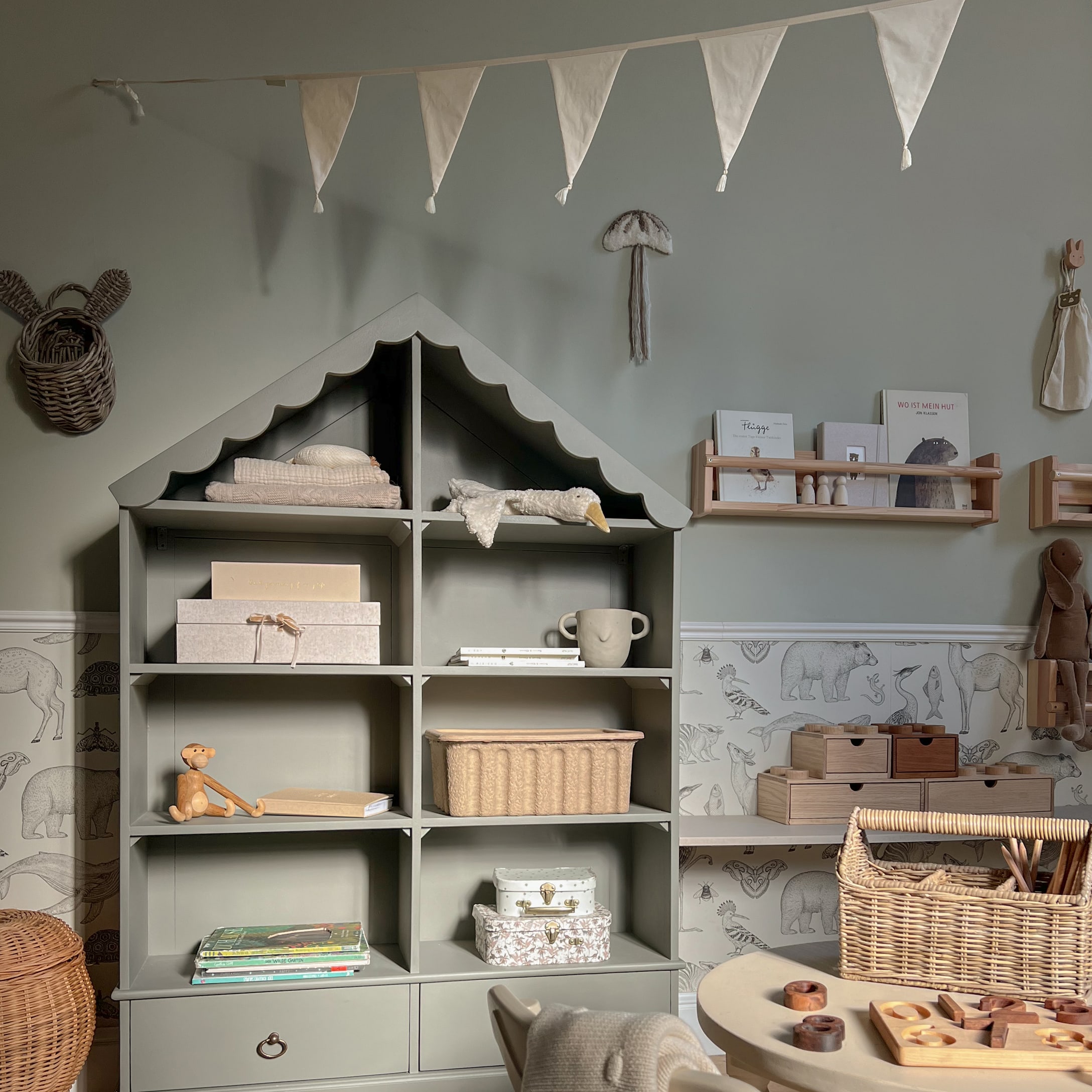 Scaffale grigio in legno a forma di casa con decorazioni e giocattoli in camera dei bambini