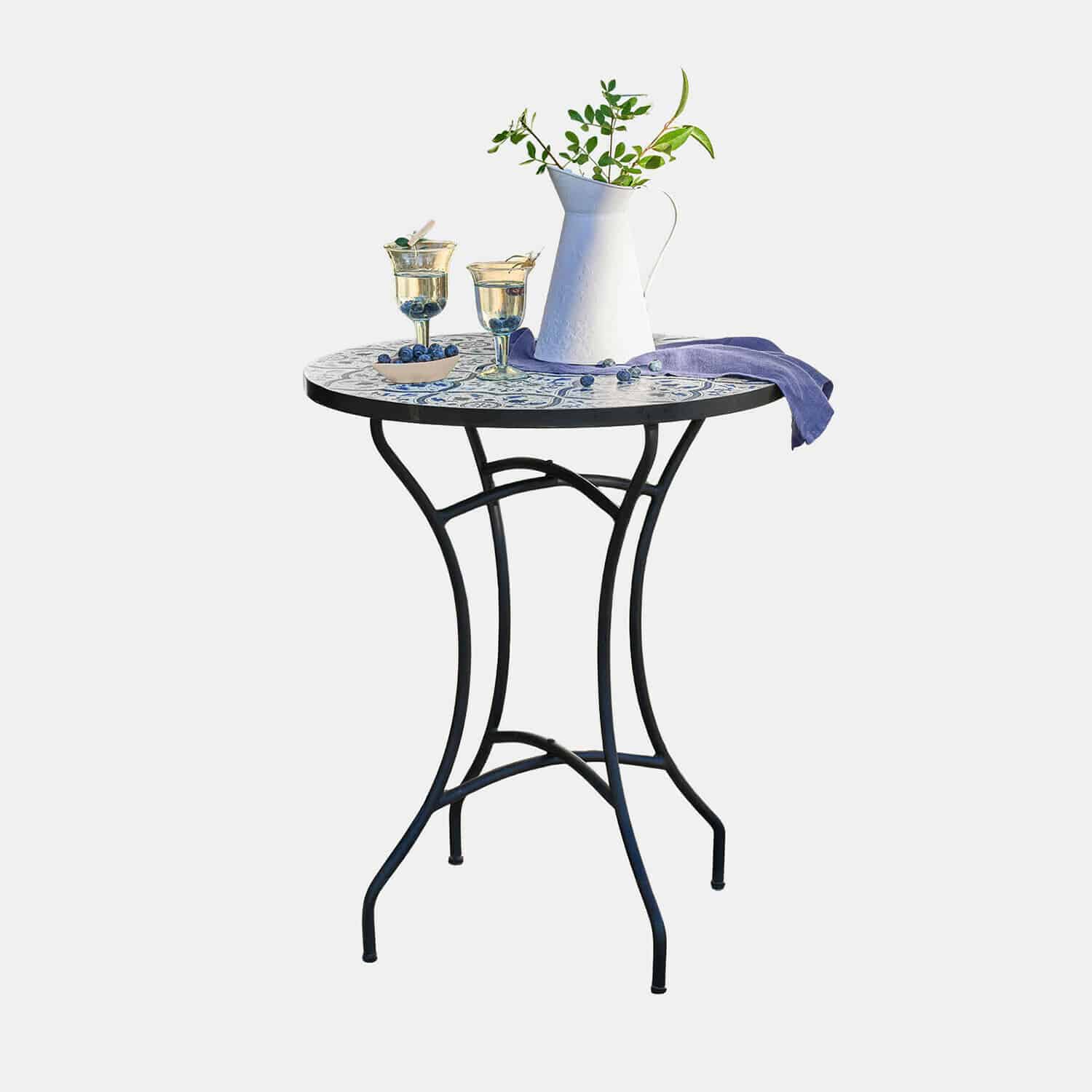 Tavolo Giulessa Tavolo rotondo con gambe in metallo e piano in mosaico bianco e blu, decorato con brocca e bicchieri
