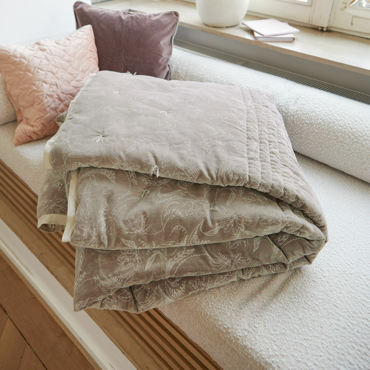 Trapunta Olicianne Coperta trapuntata beige con delicato motivo floreale su divano chiaro in soggiorno
