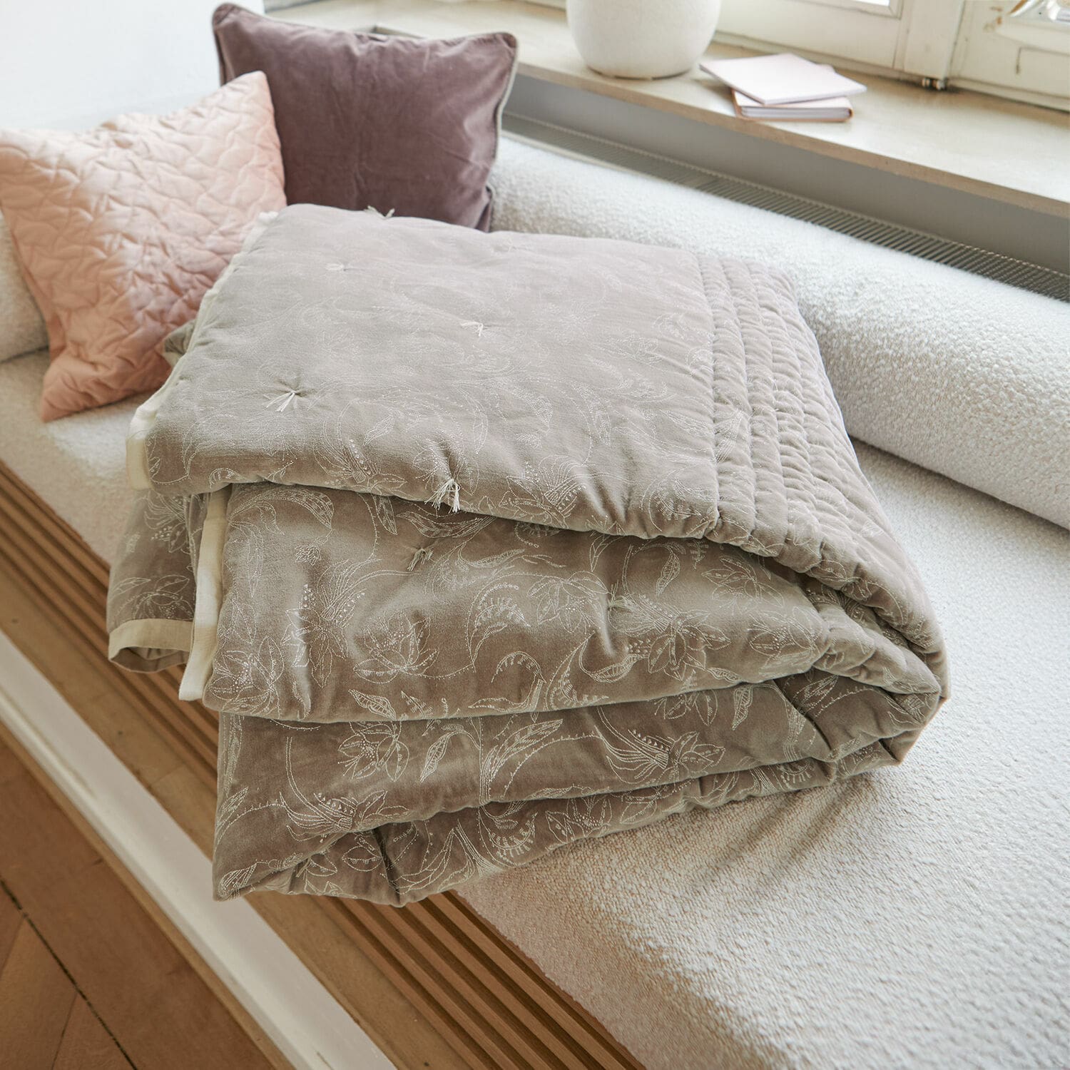 Trapunta Olicianne Coperta trapuntata beige con delicato motivo floreale su divano chiaro in soggiorno