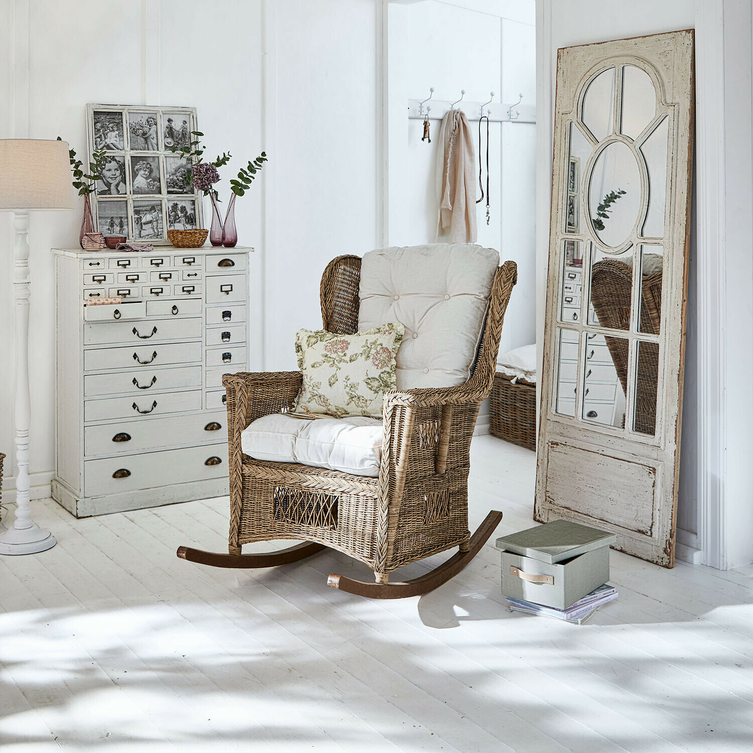 Sedia a dondolo Jeveren Sedia a dondolo in rattan con cuscini crema in interno luminoso con pavimento bianco