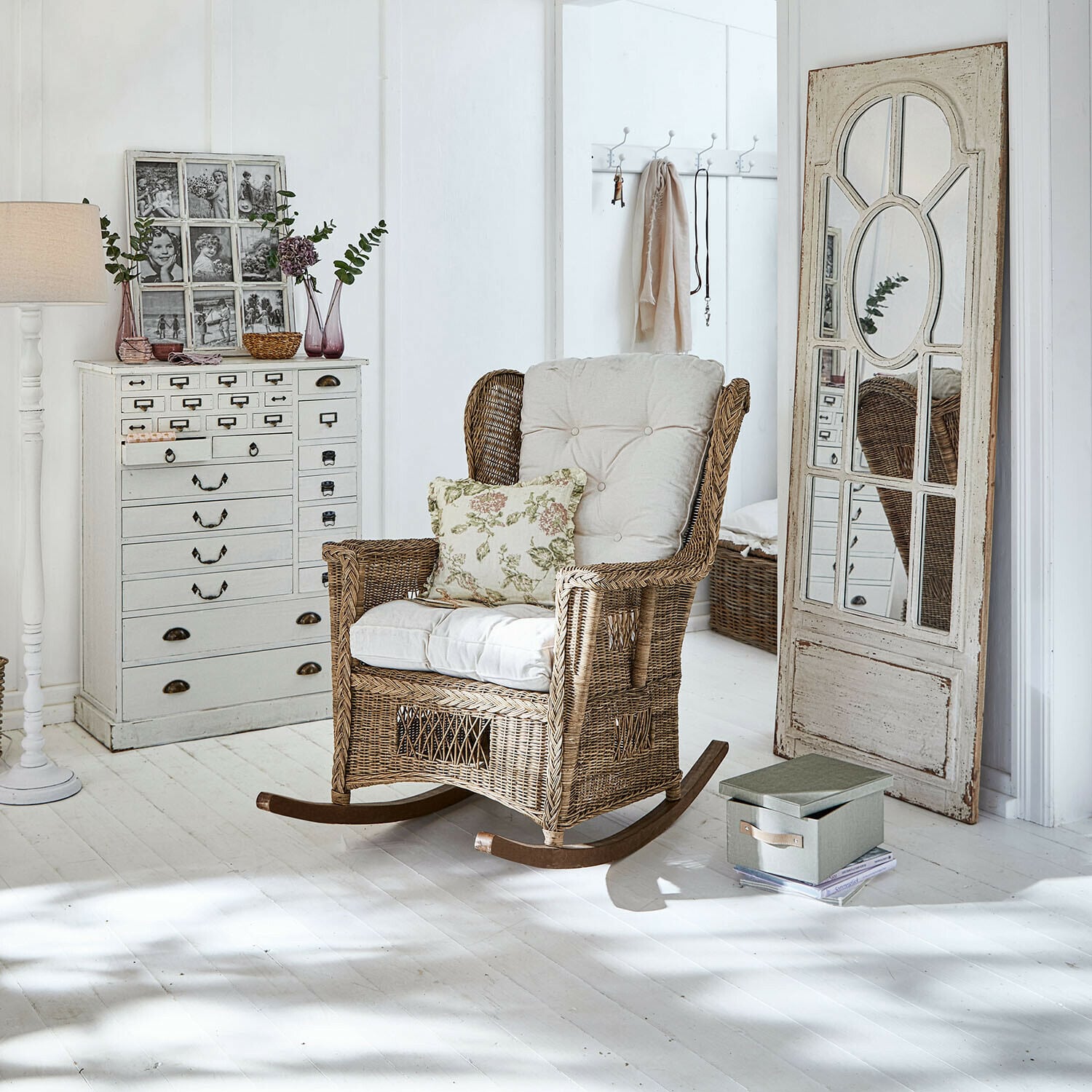 Sedia a dondolo Jeveren Sedia a dondolo in rattan con cuscini crema in interno luminoso con pavimento bianco