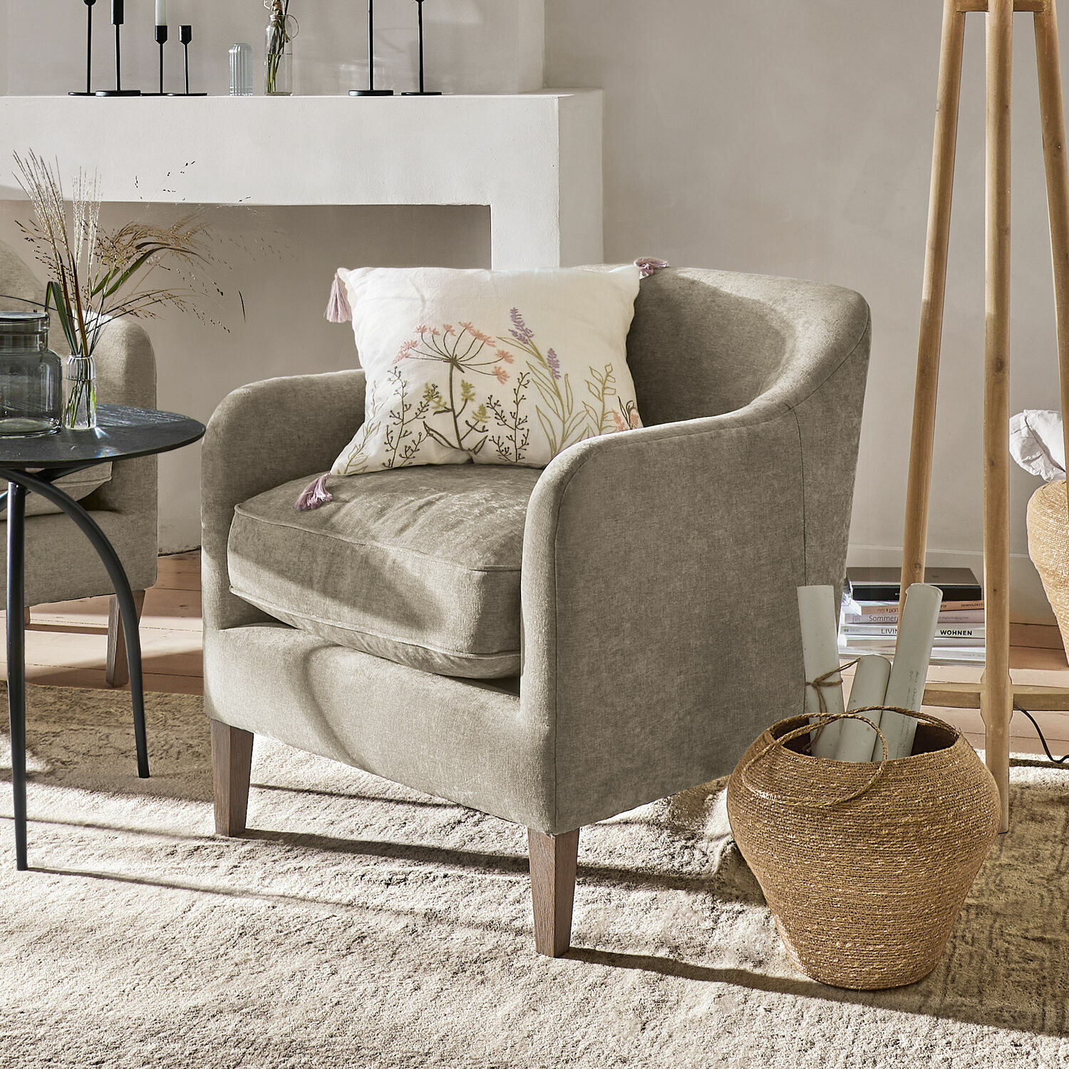Poltrona Jefferson Poltrona beige imbottita con cuscino floreale in un soggiorno accogliente e luminoso