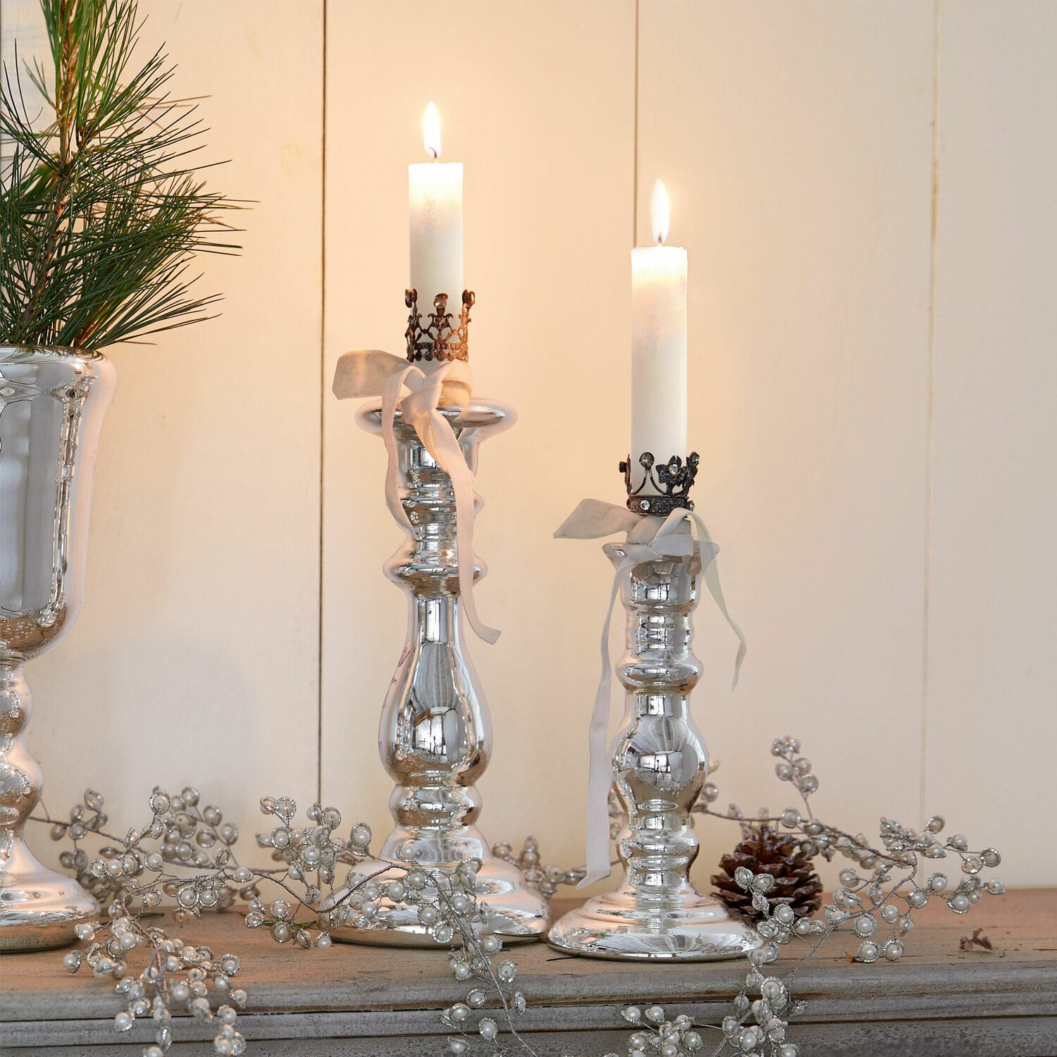 Coppia di candelieri Gao Candelabri argentati con candele bianche e nastri decorativi su superficie in legno rustico