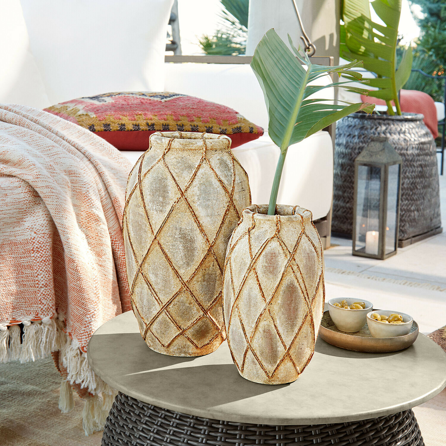 Due vasi in ceramica beige con motivo geometrico su tavolo da esterno in rattan