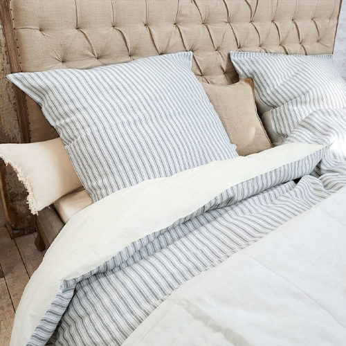Biancheria da letto in cotone a righe grigie su testiera trapuntata beige, elegante e confortevole