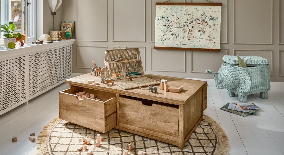 Tavolino in legno con cassetti e giocattoli animali su tappeto in stanza bambini luminosa