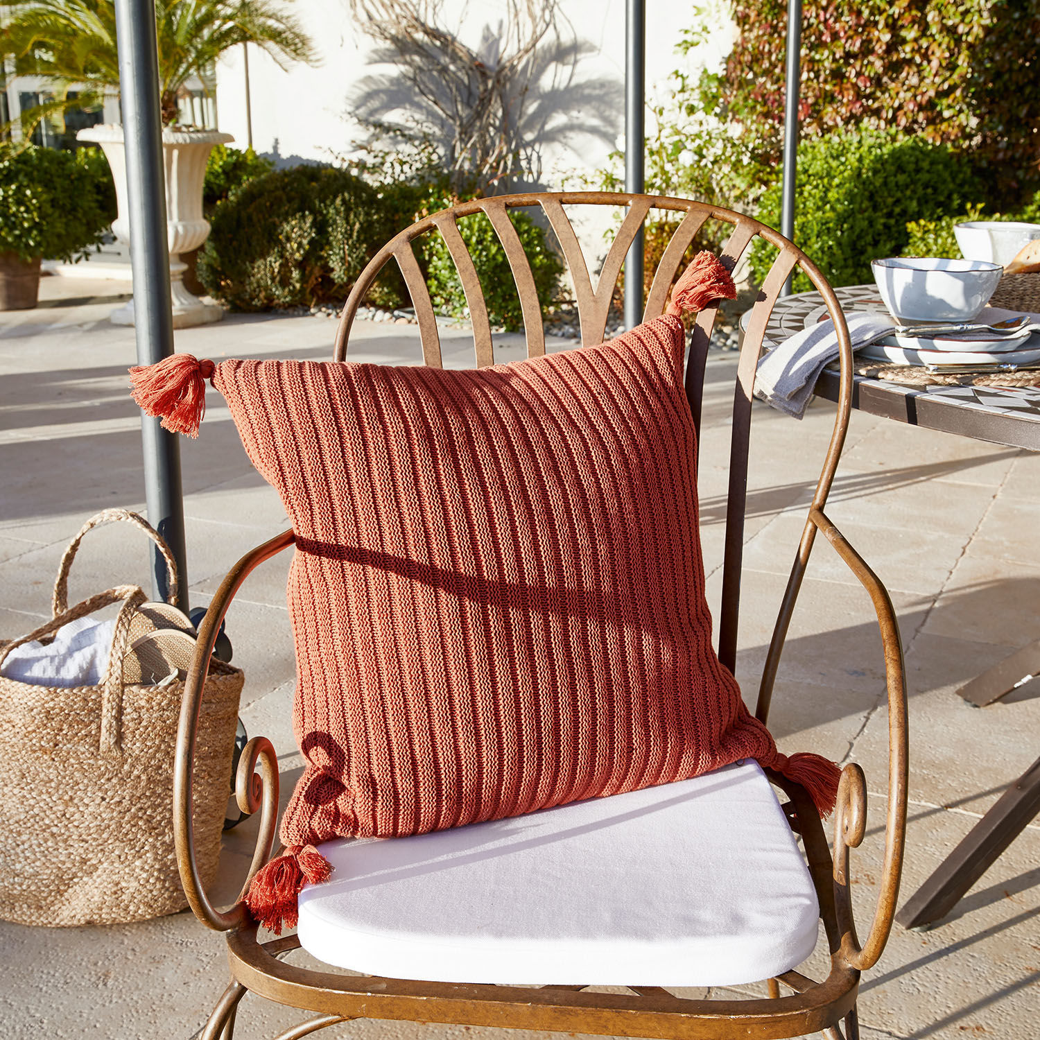 Copricuscino Bally Cuscino decorativo rosso lavorato a maglia con nappine su sedia in metallo in terrazza