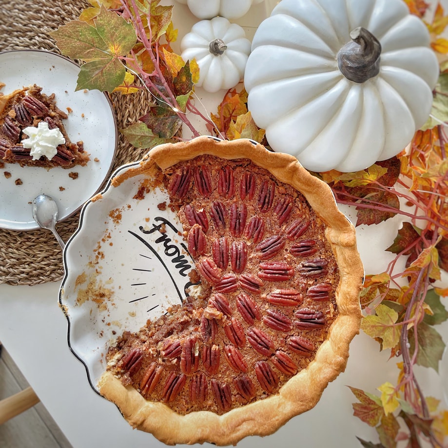 Torta di noci pecan su piatto con decorazioni autunnali e zucche bianche