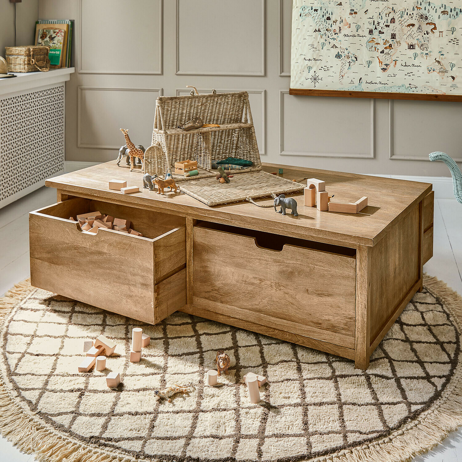 Tavolino in legno con cassetti e giocattoli su tappeto rotondo in stanza bambini luminosa
