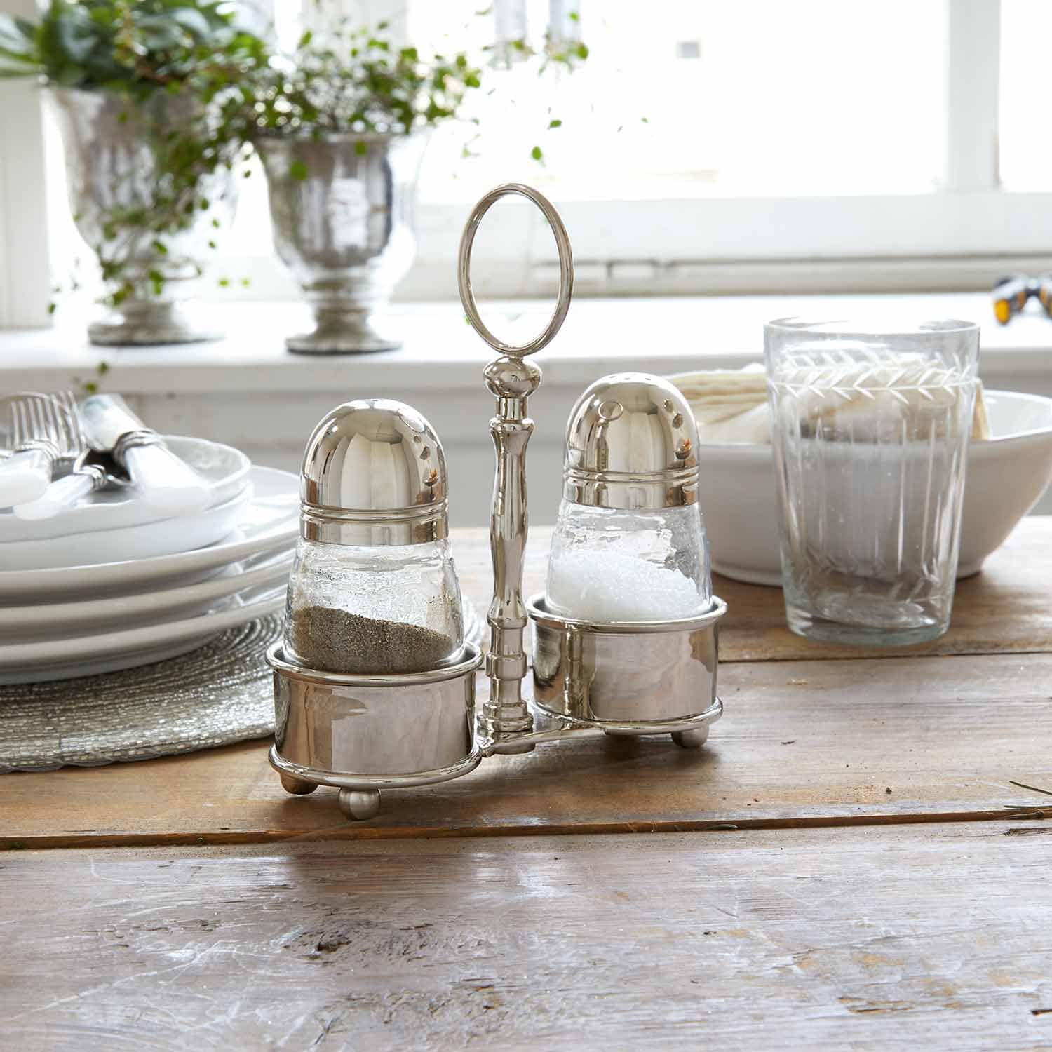 Set di saliera e pepiera in acciaio inox su tavolo in legno in cucina luminosa
